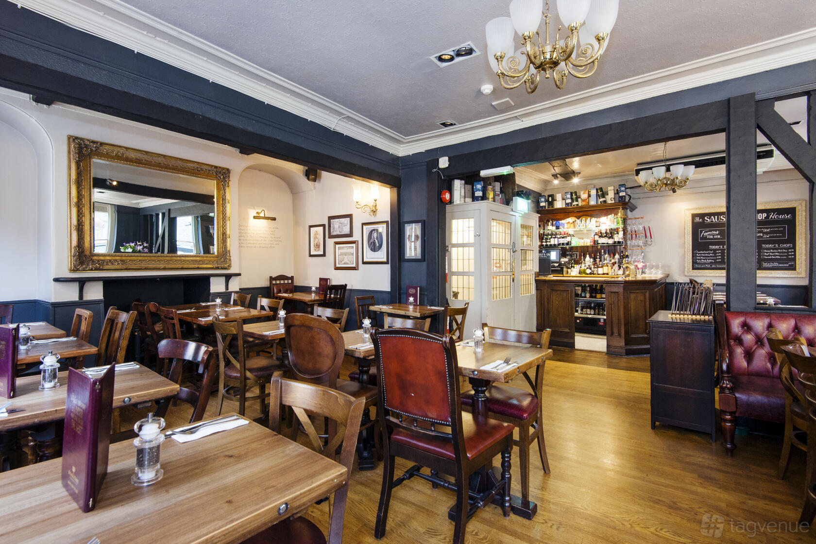 A pub dining room with wooden tables, leather chairs, framed artwork, and a large ornate mirror at Ye Olde Watling.