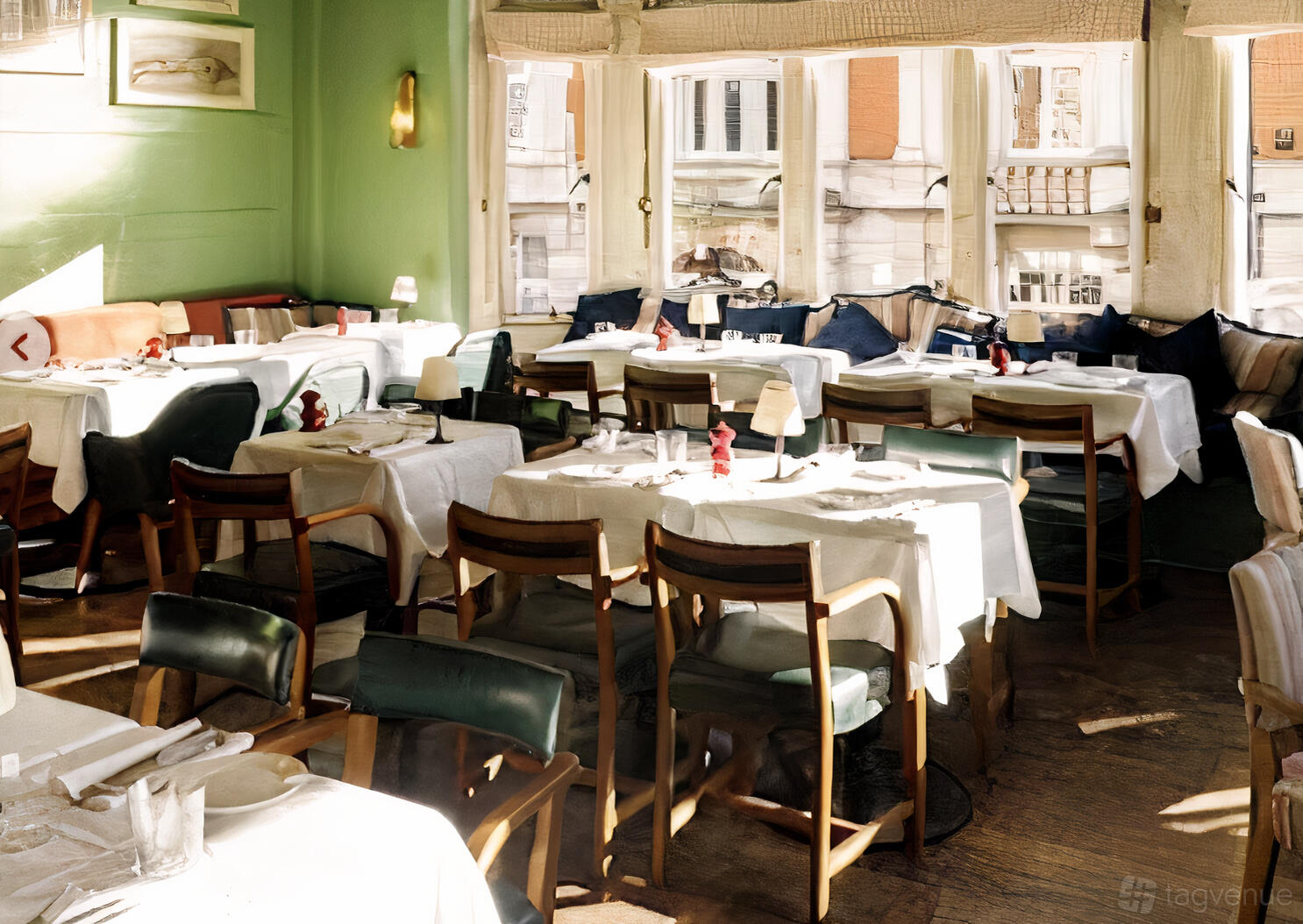 A dining room with large windows, white tablecloths, cushioned chairs, and green walls at The Coach Makers Arms Pub Marylebone.