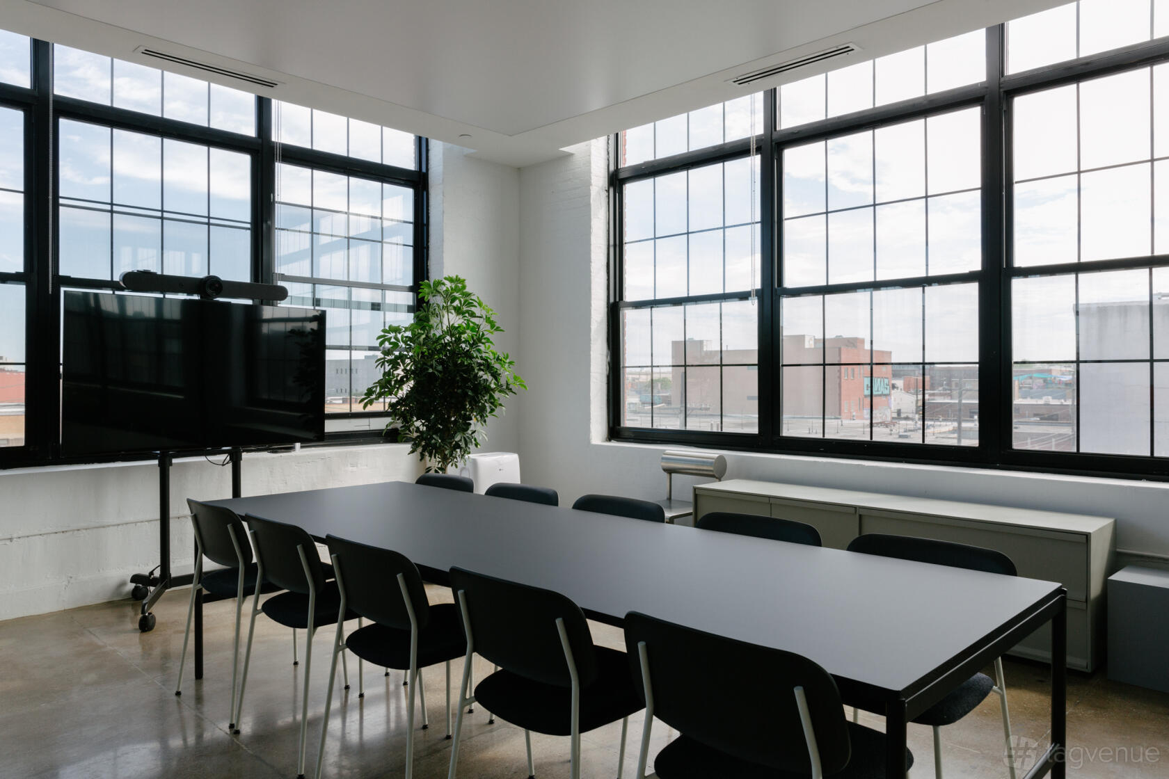 An apartment with floor-to-ceiling industrial windows, a long black table, and metal chairs at Casa Aurora.