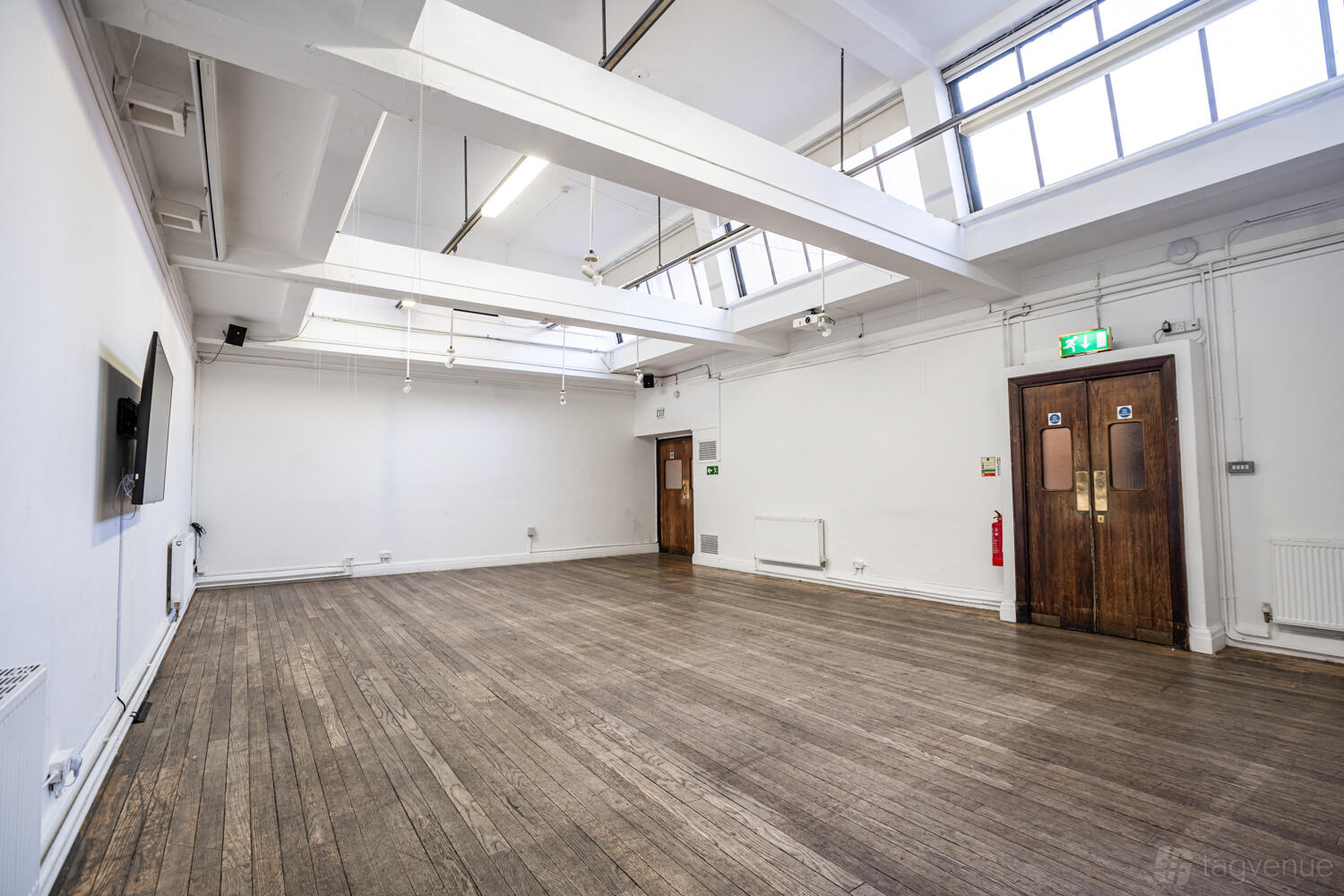 An event space with high ceilings, exposed beams, large skylights, and wooden floors at Conway Hall.