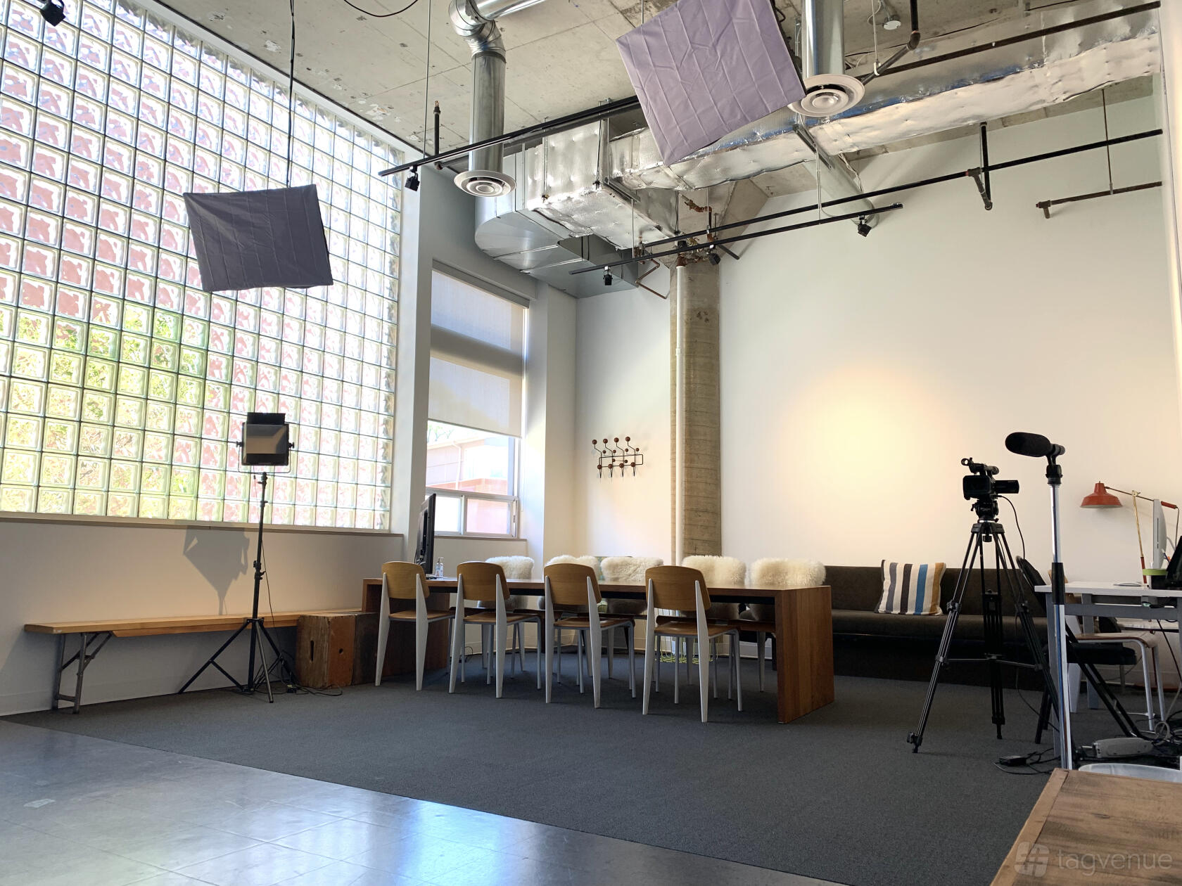 A photo studio with large glass block windows, high ceilings, a long meeting table, and lighting equipment at Powerhouse Casting