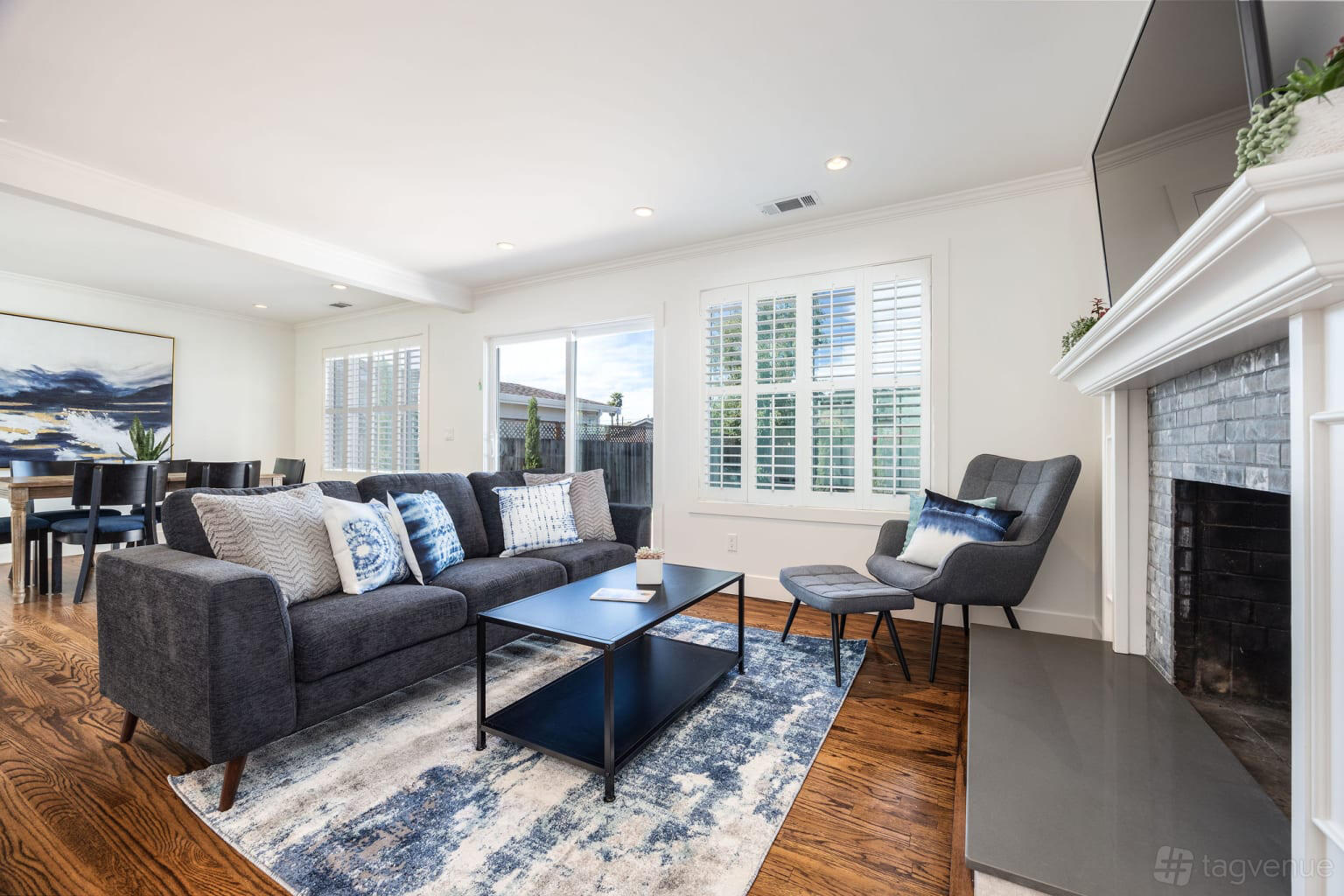 An apartment living room with a gray sectional sofa, patterned rug, fireplace, and large windows at Quiet Coastal Get Away Home.