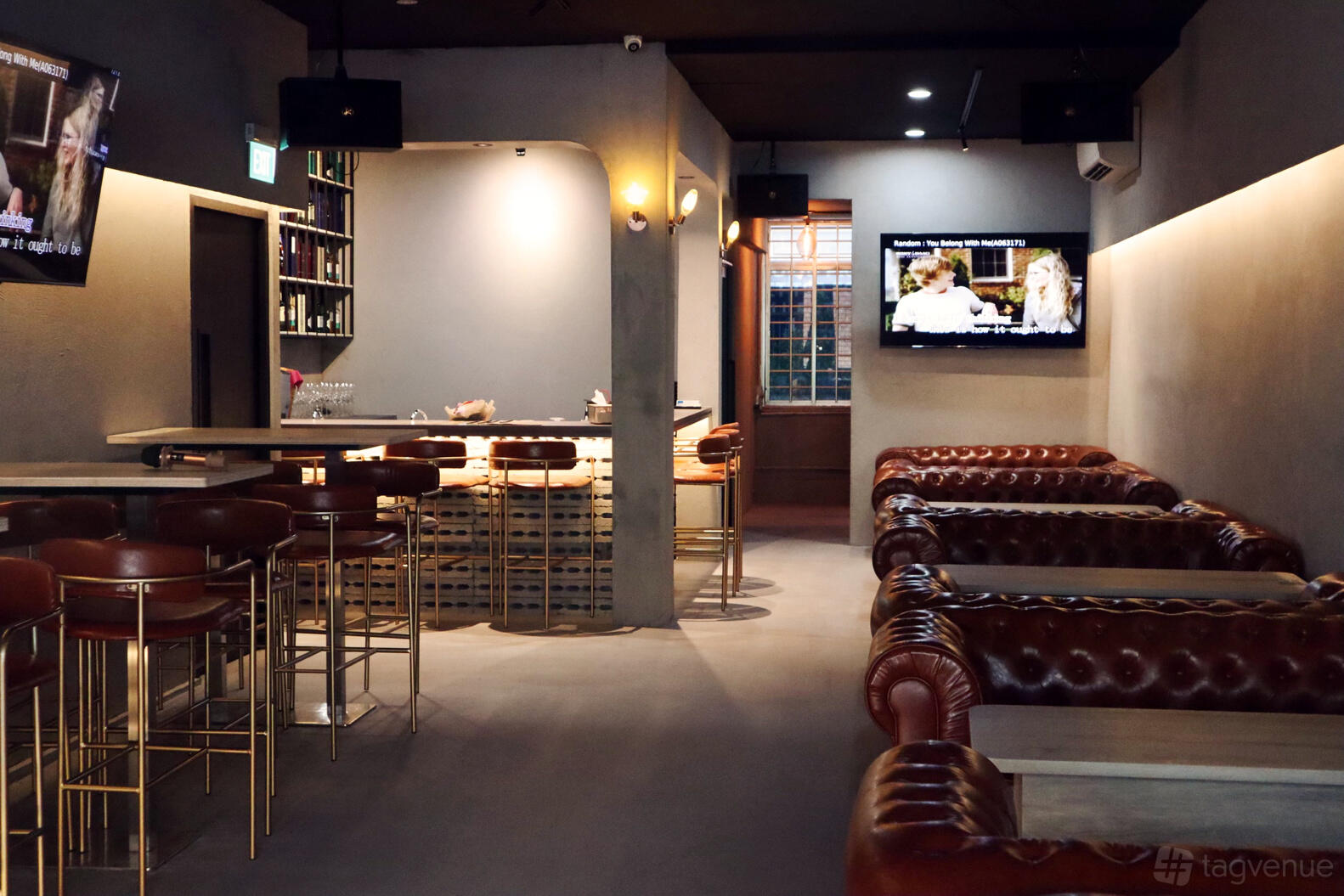 An event space in a karaoke bar with tufted leather sofas, bar seating, and wall-mounted TVs at V Lounge.