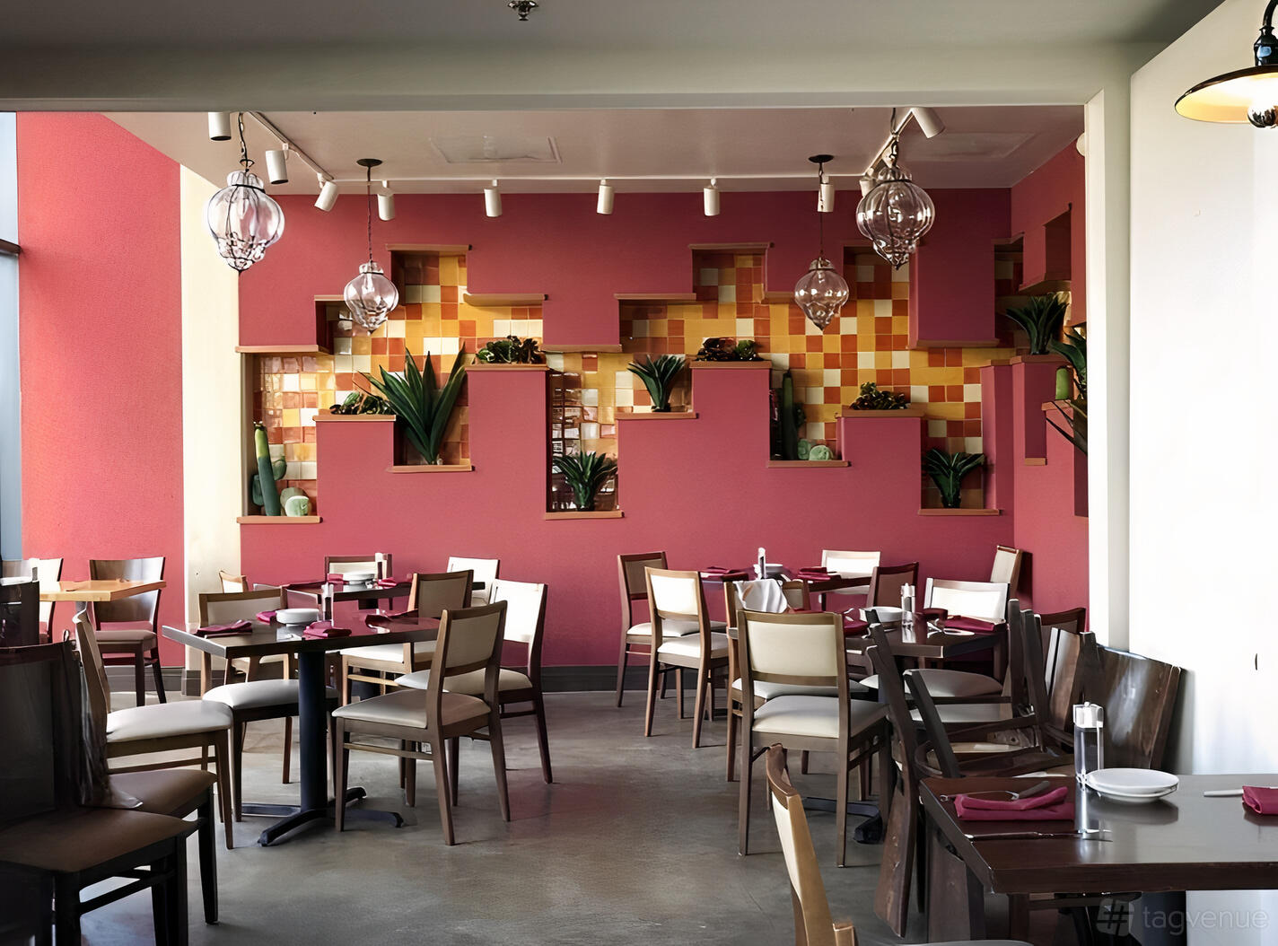 A function room with geometric wall shelves, potted plants, track lighting, and arranged dining tables at Agua 301.