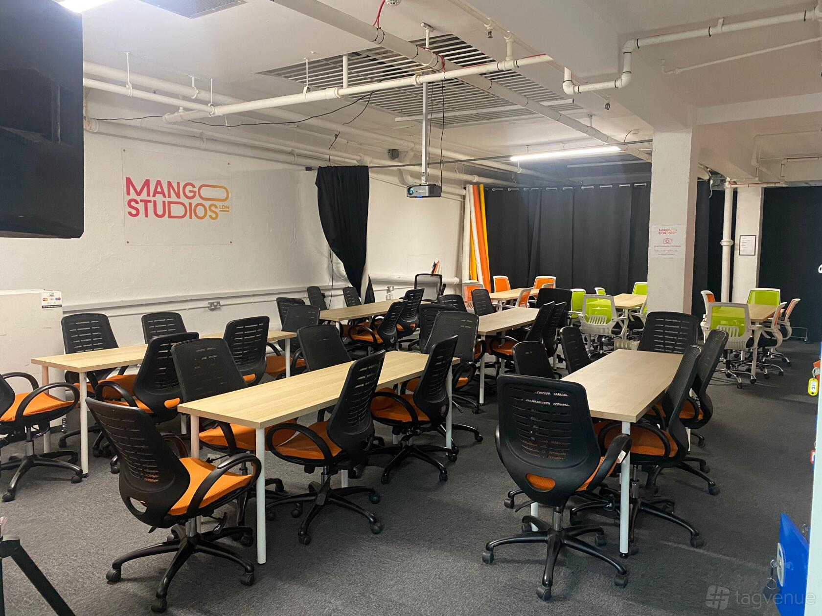An event venue with rows of light wood tables and orange-and-black office chairs at MangoStudiosLDN.