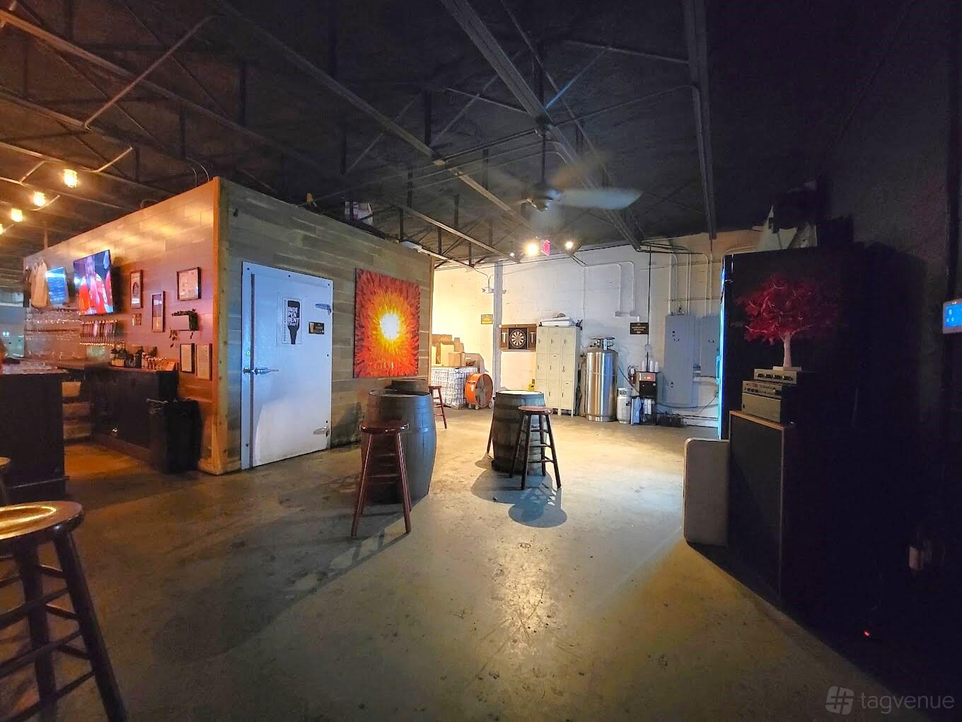 A brewery with industrial ceilings, concrete floors, barrels, and exposed ductwork at Lost City Brewing Company.