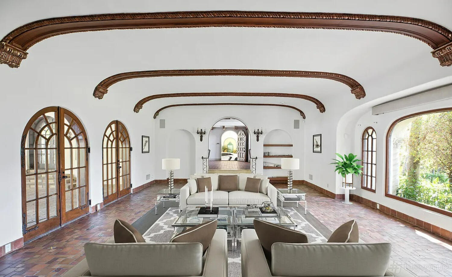 An event venue with arched wood-trimmed ceilings, large arched windows, and a lounge area at The Sunset Estate.