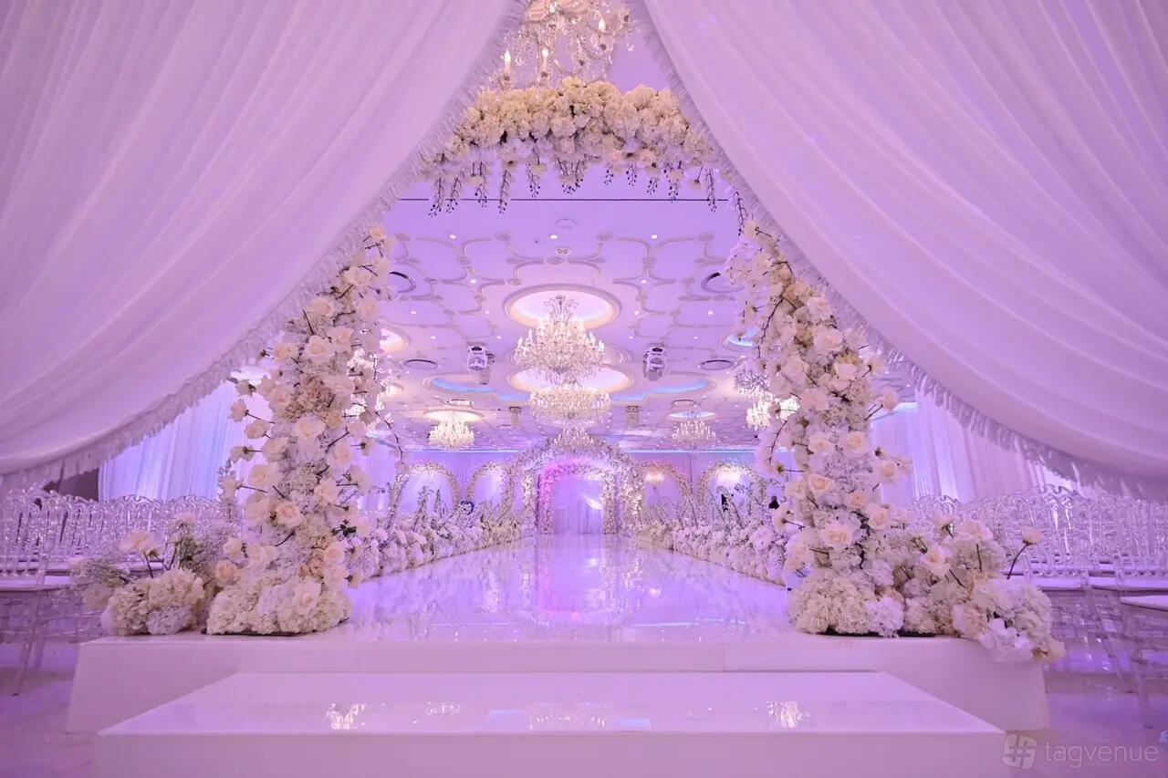 An event venue with a flower-adorned arch, crystal chandeliers, and a glossy aisle at Da Mikele Illagio.