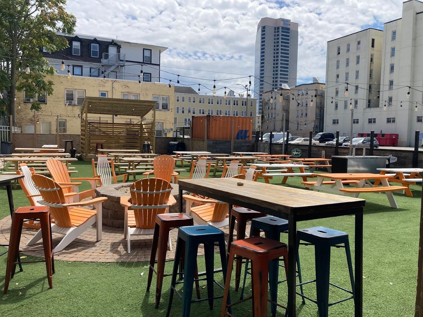 An outdoor space with picnic tables, Adirondack chairs, and string lights at Tennessee Avenue Beer Hall.