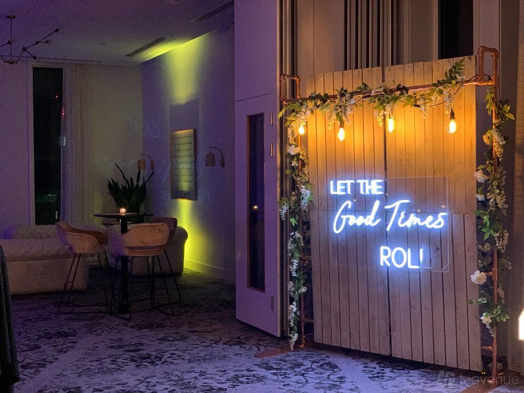 A hotel hall with a wooden backdrop featuring neon signage and hanging bulbs at voco Manchester