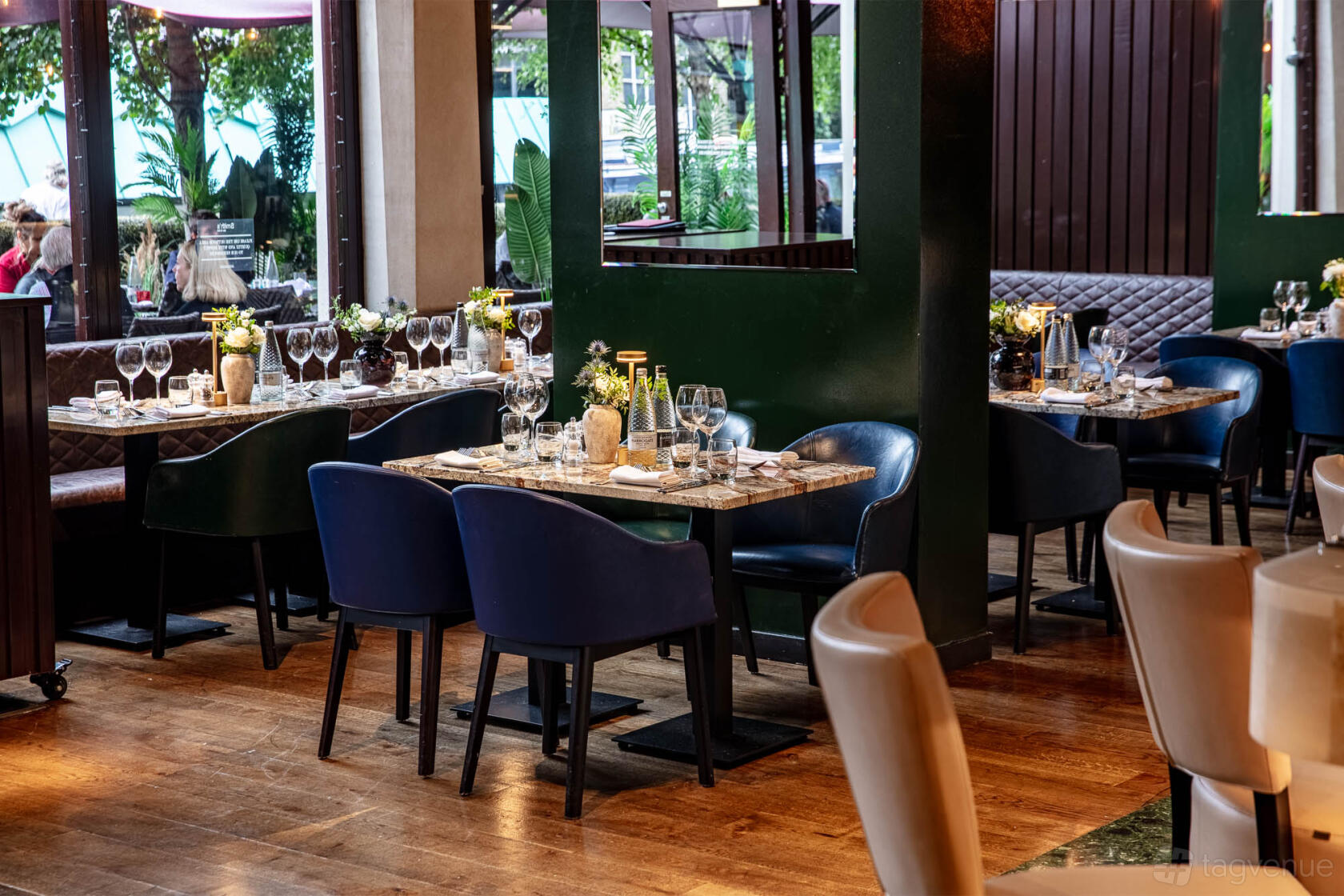 An event space in a restaurant with blue armchairs, set tables, and large windows at Smith's Bar & Grill.