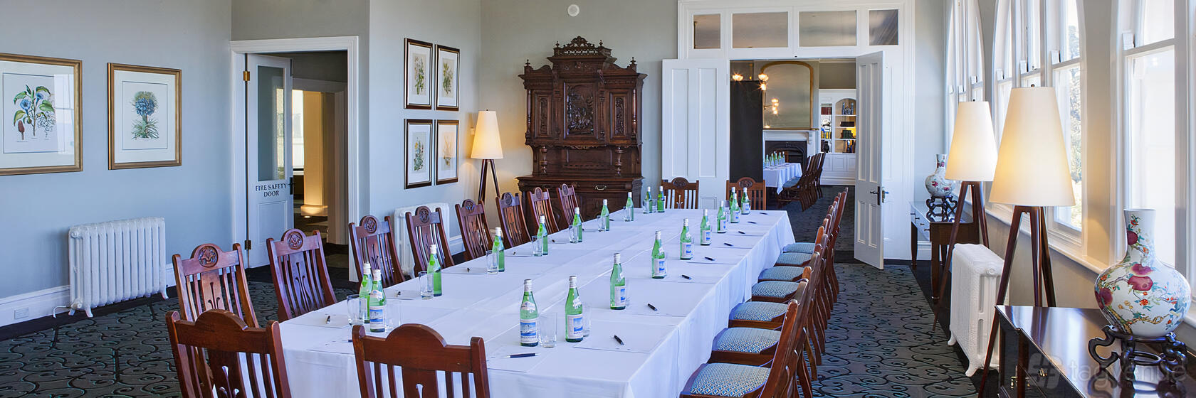 A meeting room with long rectangular tables, bottled water, and wooden chairs at Hydro Majestic Blue Mountains.