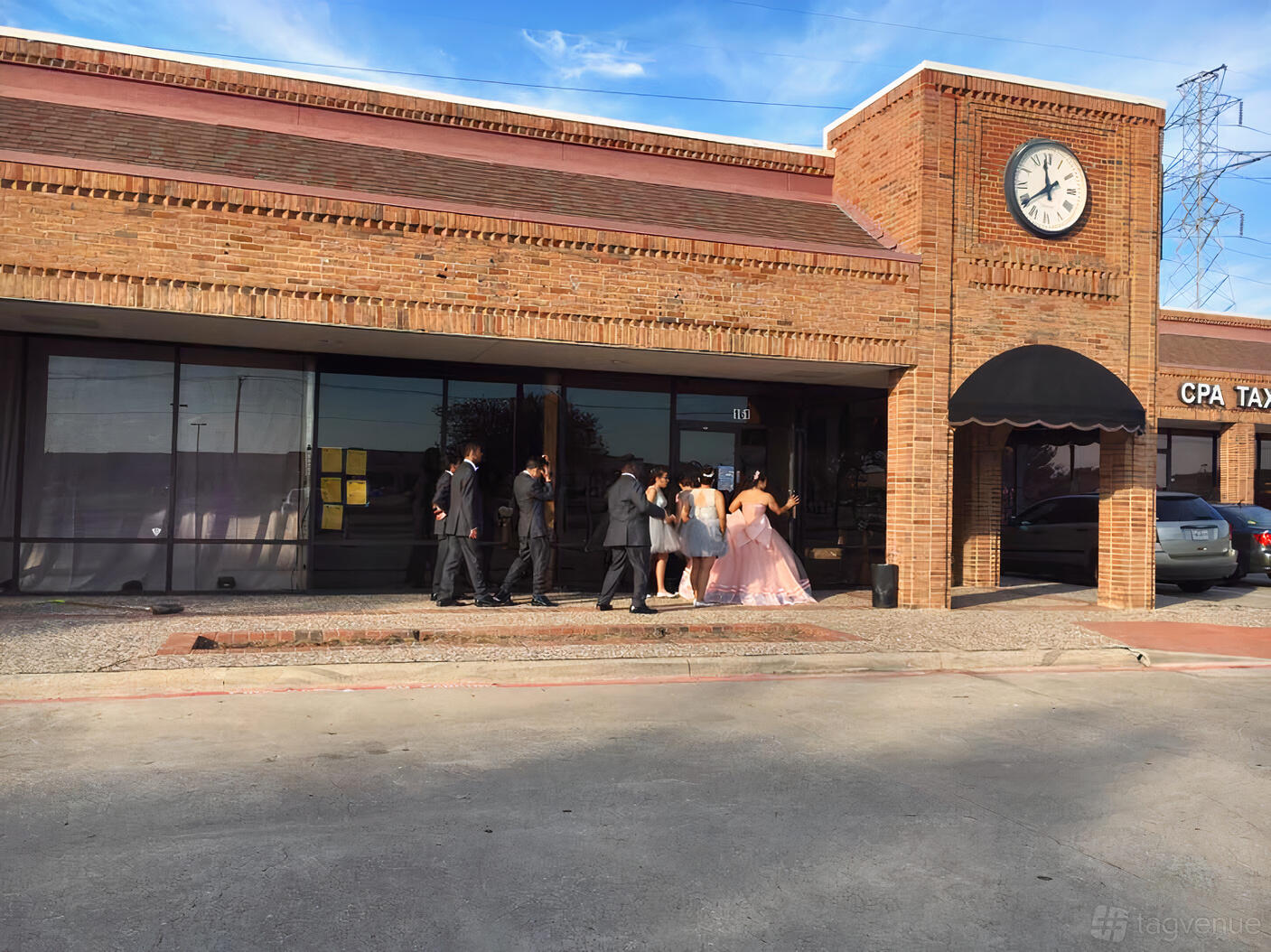 A brick hall exterior with large front windows, black awning, and a clock tower at Reyes Ballroom 2.