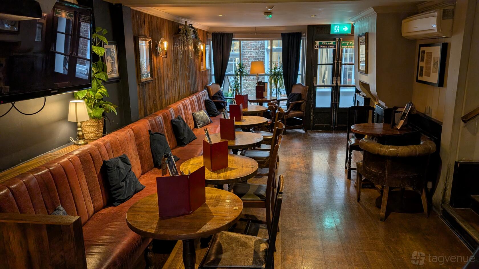 A pub dining room with brown leather banquette seating, wooden tables, and warm lighting at White Horse.