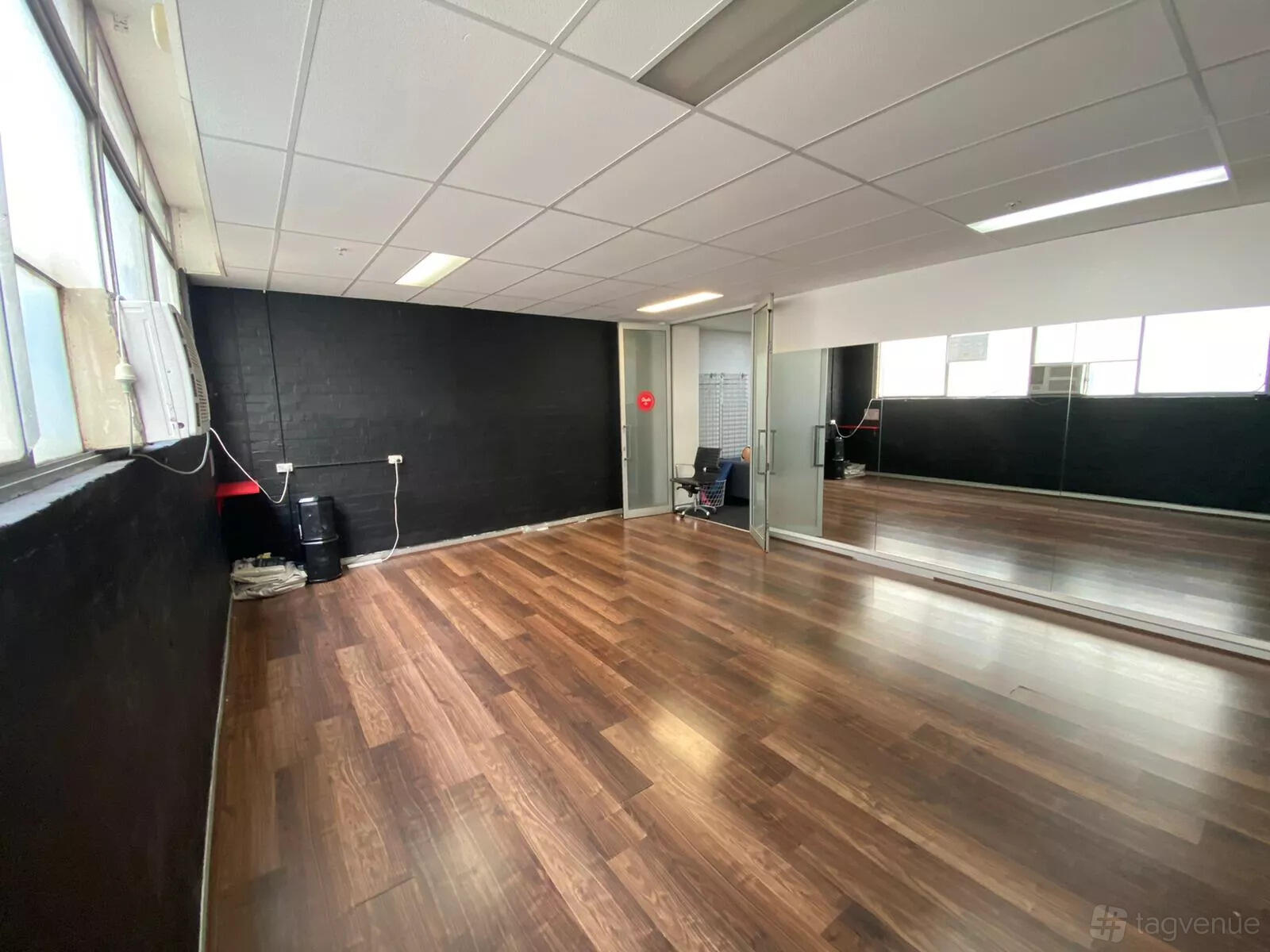 A dance studio with hardwood floors, wall mirrors, and large windows at Latin Dance Australia.