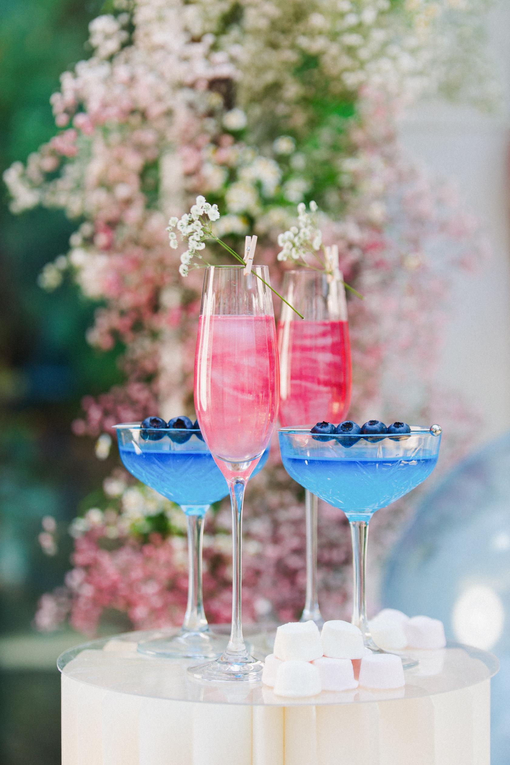 Colorful cocktails with blueberries and baby's breath flowers, set against a floral backdrop at The Roseate Edinburgh.