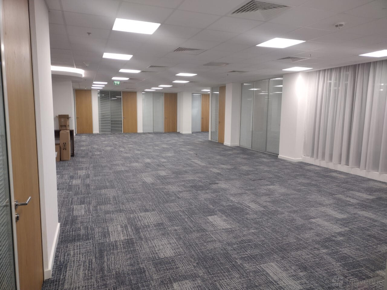 A function room with grey carpeted flooring, glass partitions, and ceiling lights at Marlin Waterloo.