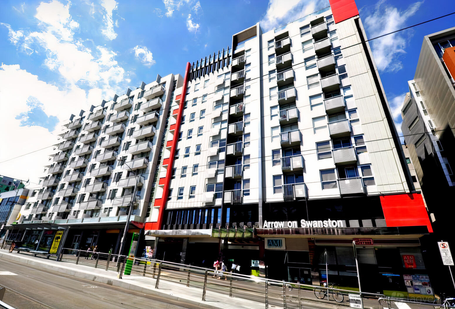 A hotel with a modern multi-story facade, glass balconies, and ground floor signage at Arrow on Swanston.