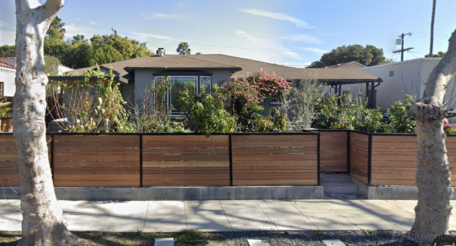 A versatile event space with a modern wood fence, lush greenery, and a single-story house at MooseCat Recording.