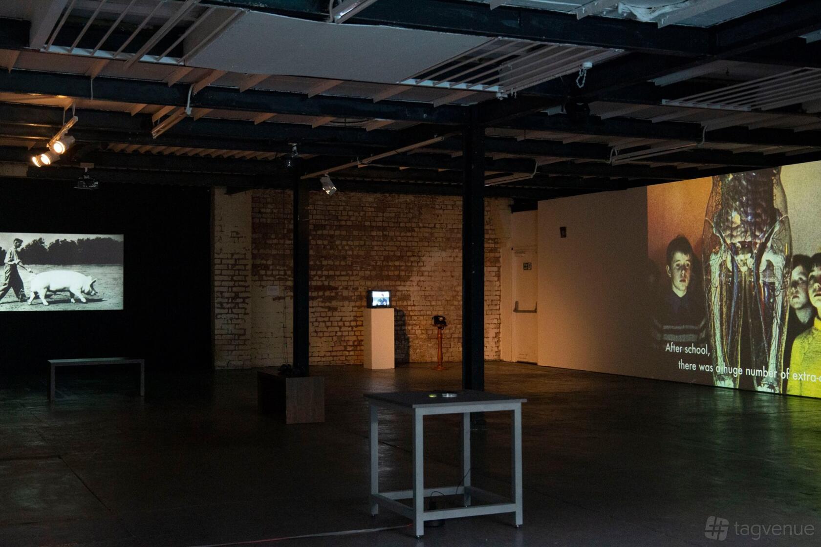 An event venue with exposed brick walls, industrial ceiling, and projected art displays at Centrala Space.