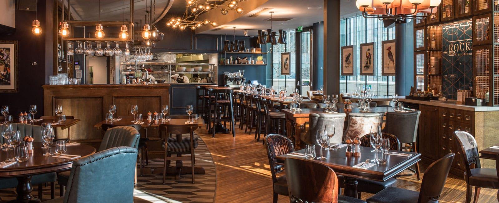 A restaurant with floor-to-ceiling windows, wooden floors, dark wood tables, and pendant lighting at Rocket.