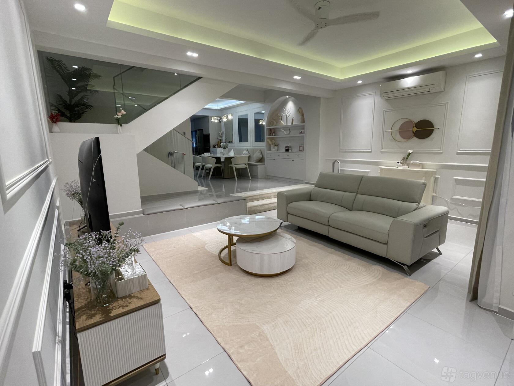 A living area with a light gray sofa, round coffee table, soft rug, and open view to dining space at White Modern Minimalist Landed Home.