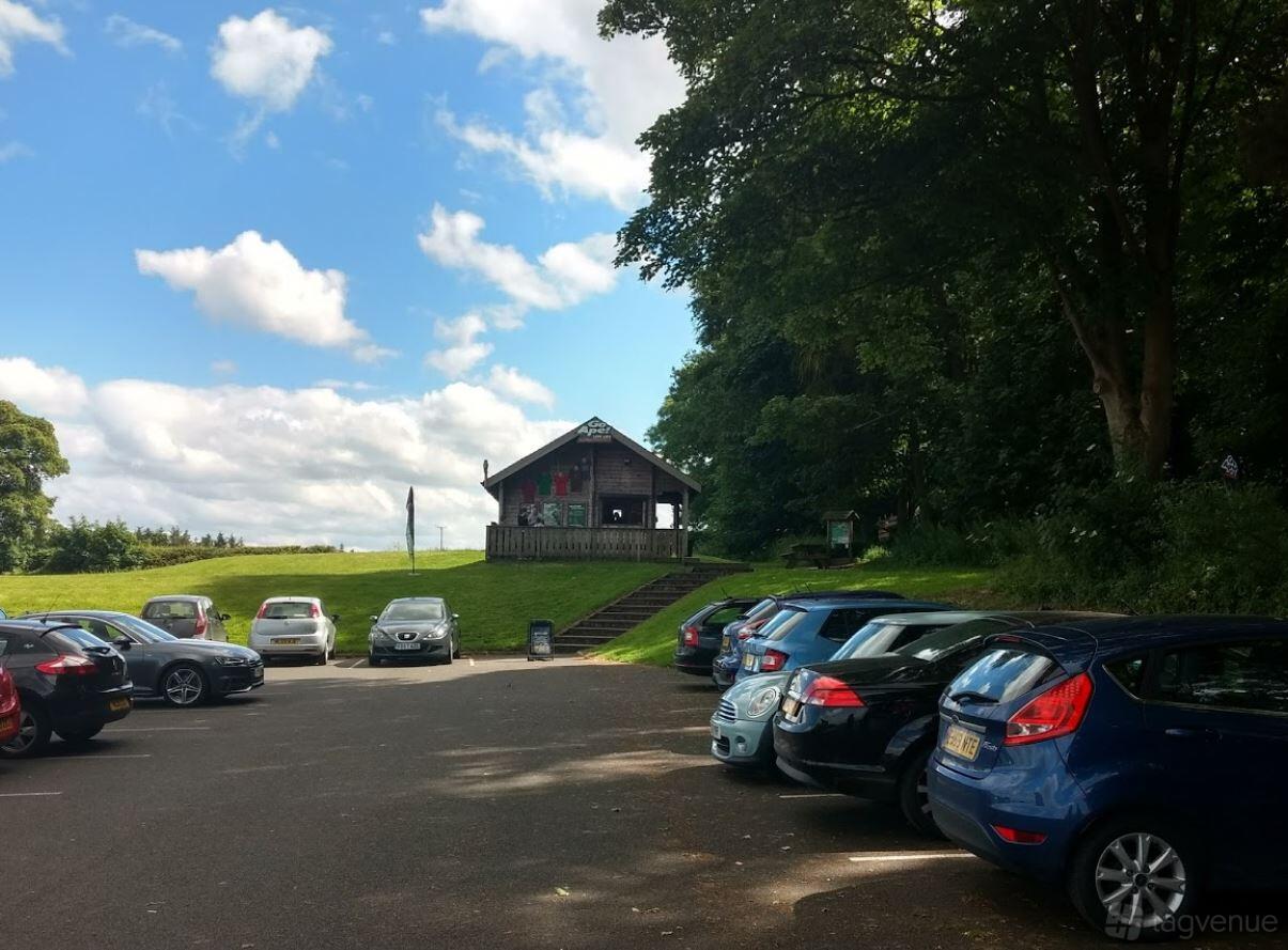 An outdoor venue with a gravel parking lot, grassy fields, and a wooden cabin at Go Ape Matfen.