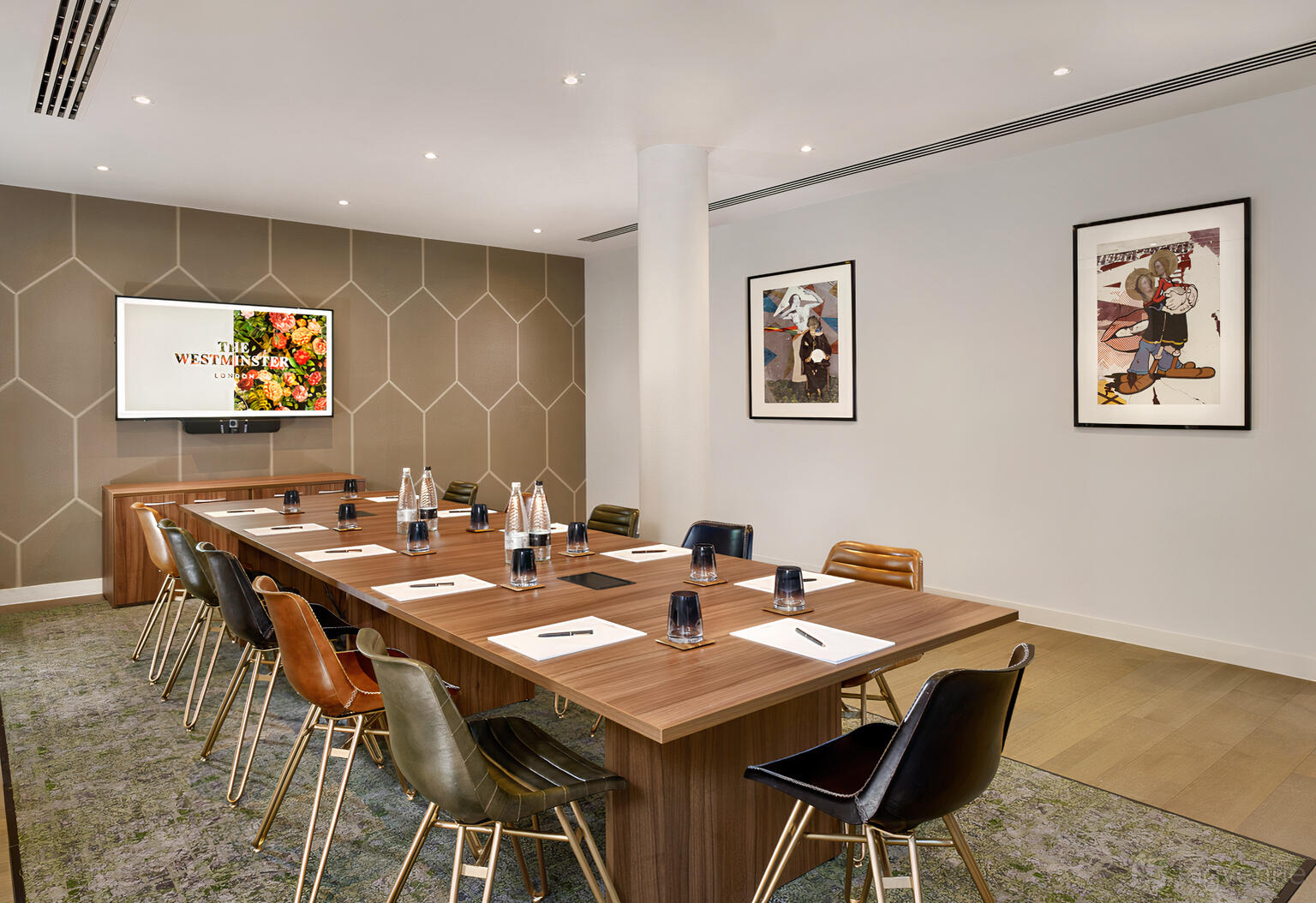 A hotel meeting room with a wooden conference table, leather chairs, wall-mounted screen, and framed art at The Westminster London.