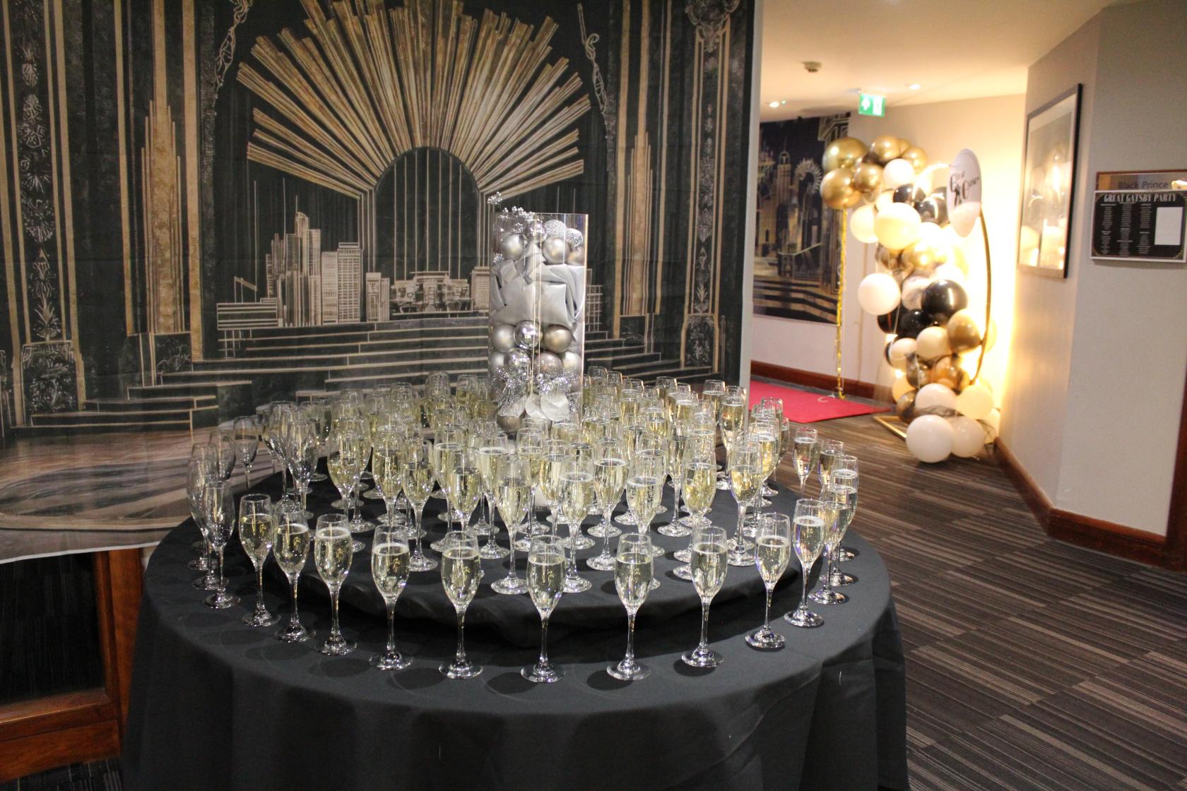 An event space with a round table featuring filled champagne flutes and an art deco backdrop at Holiday Inn London Bexley
