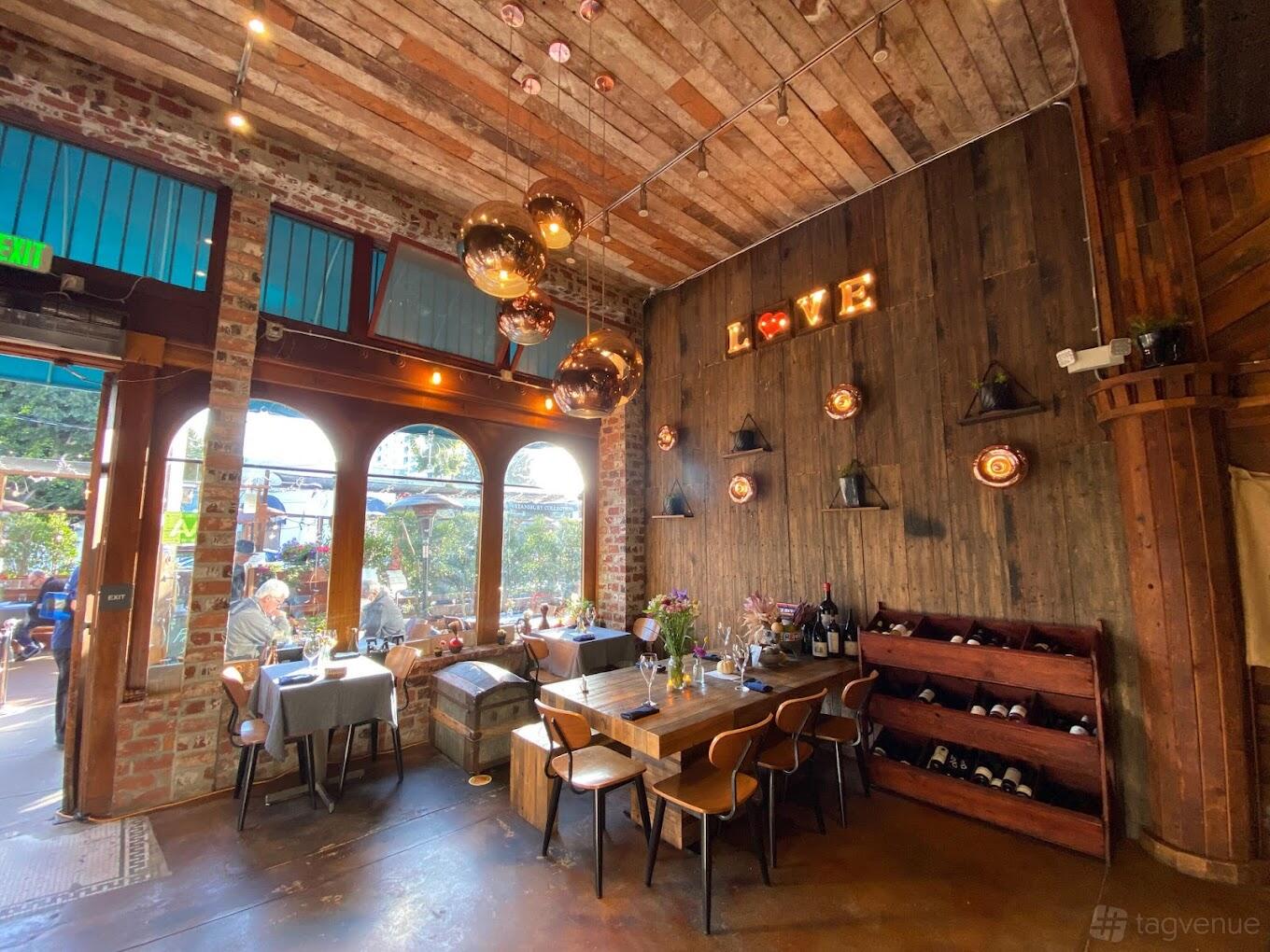 A restaurant with exposed brick walls, wooden ceiling, globe pendant lights, and a LOVE sign at Papille Gustative.