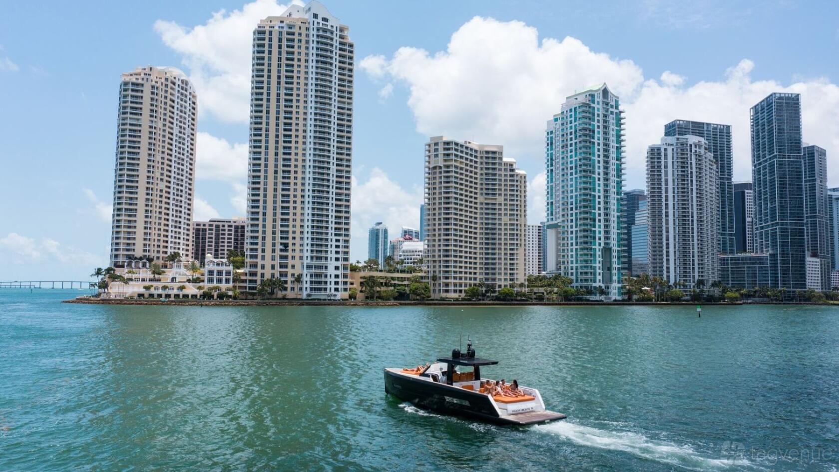 A sleek yacht cruising on the water with city skyscrapers in the background at Pearl Yacht Charters.