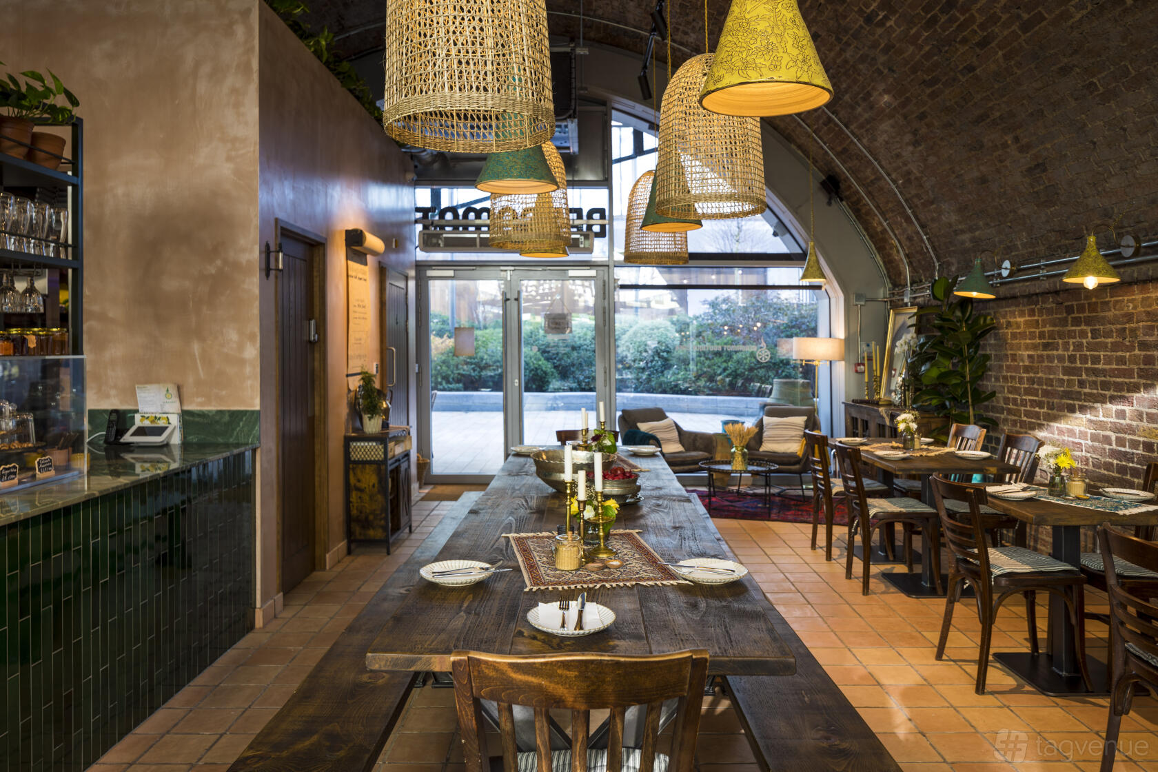 A cafe with exposed brick walls, large wicker pendant lights, and wooden tables at Bergamot Boutique Café.