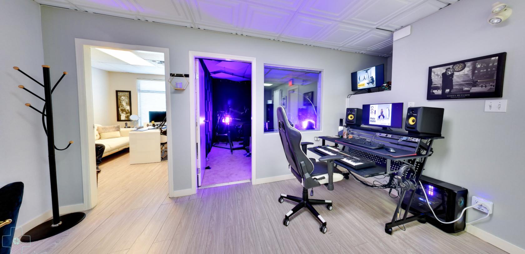 A recording room with soundproof booth, mixing desk, dual monitors, and studio speakers at Mirage Studio.