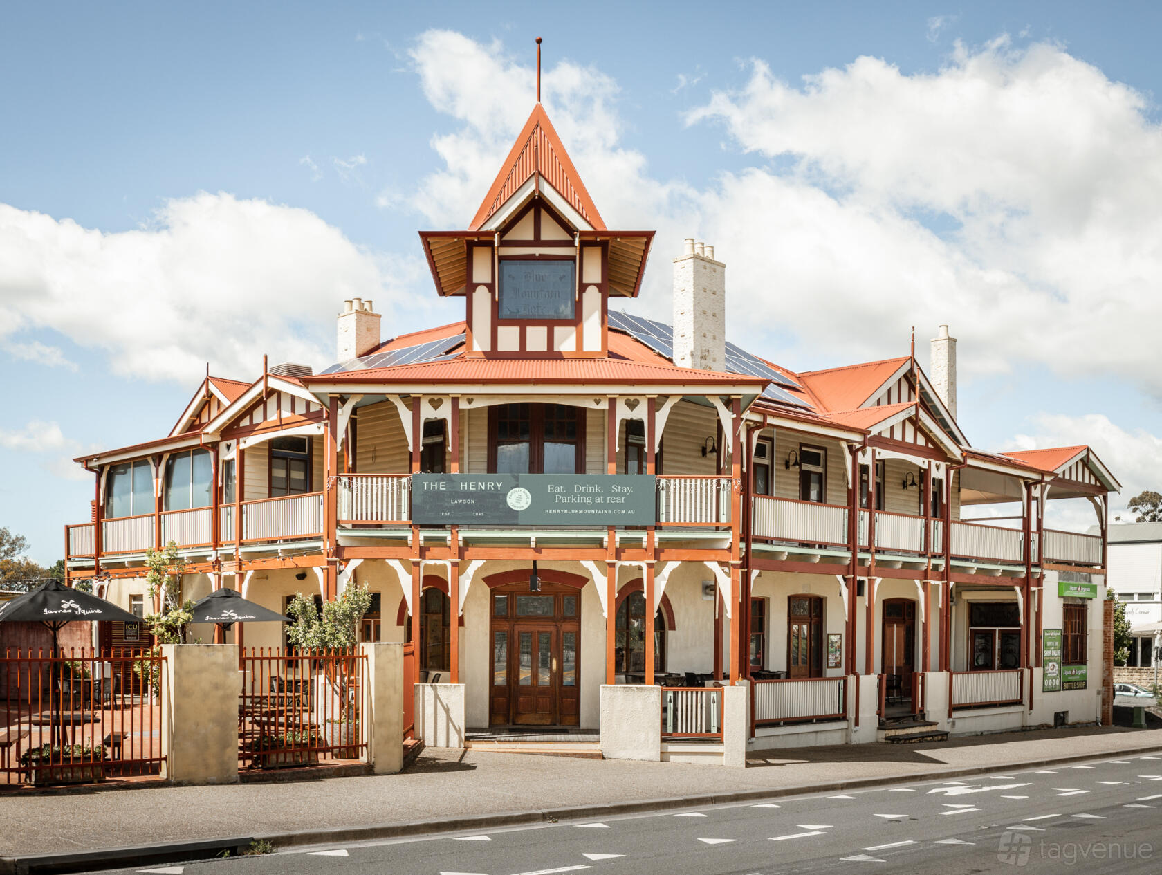 A heritage-style pub with red trim, wraparound balcony, and timber accents at The Henry.