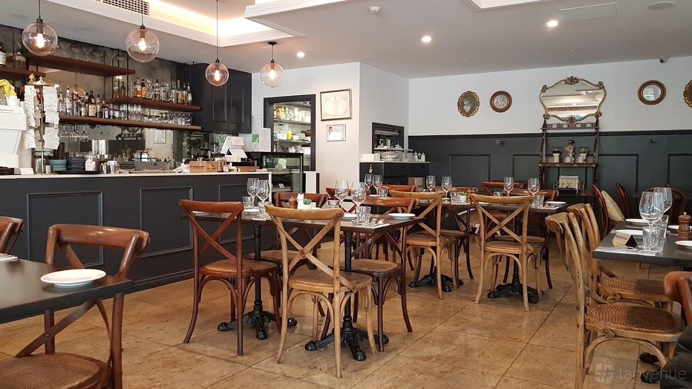 A restaurant with wooden chairs, set tables with glassware, pendant lights, and a stocked bar at Restaurant Monté.