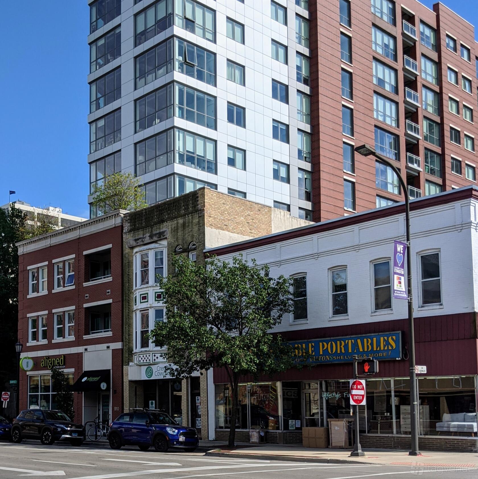 An open air venue with storefronts, tree-lined sidewalk, and a mix of brick and glass buildings at Creative Coworking.