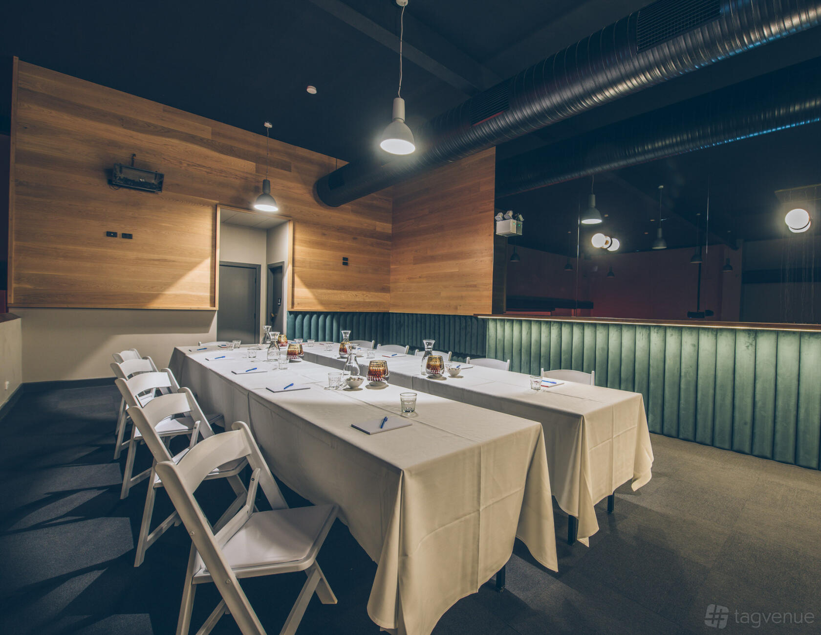 A function room with two long tables covered in white linens and folding chairs at DIAGORA EVENTS.