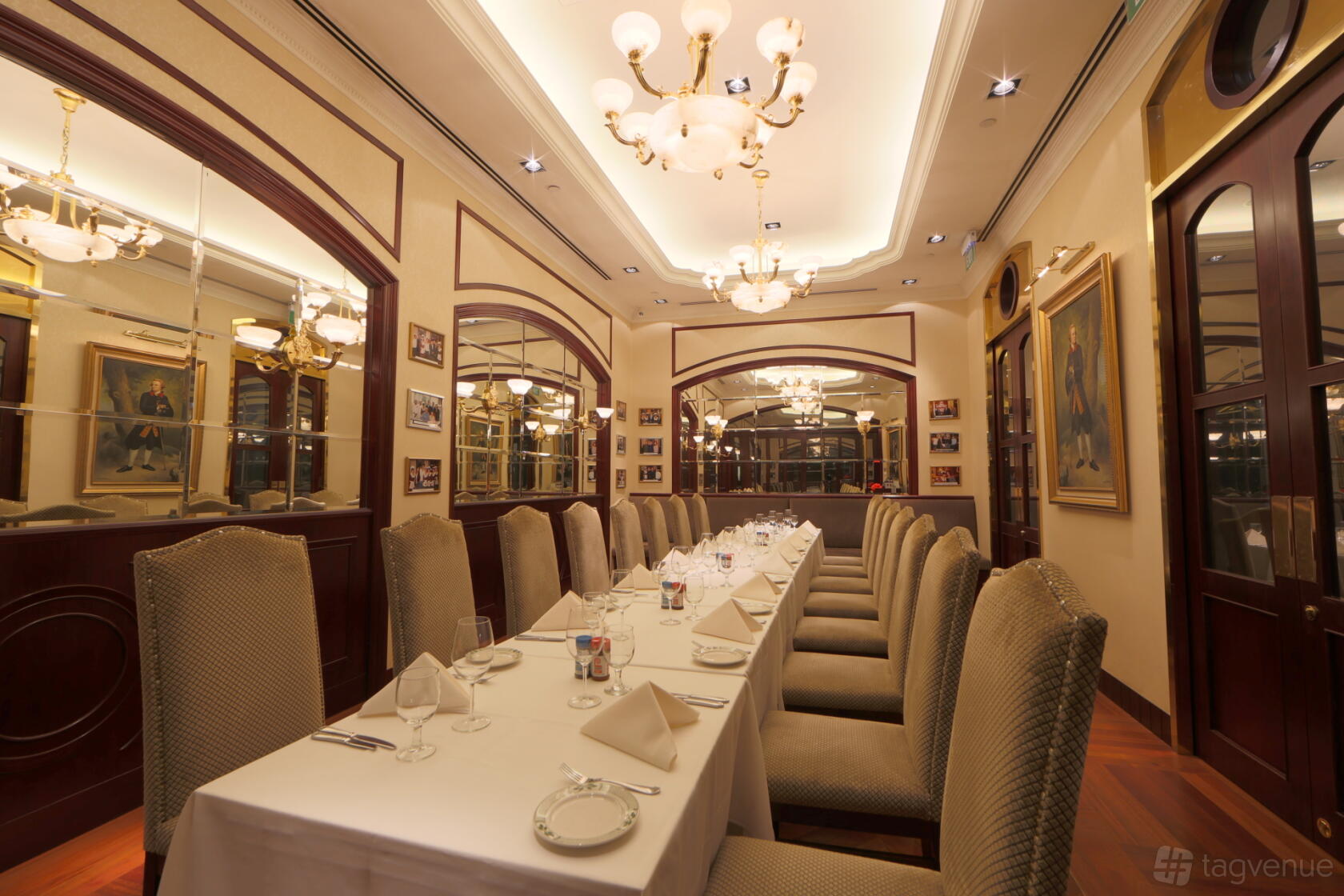 An event space in a restaurant with a long banquet table, high-backed chairs, and chandeliers at Lawry's The Prime Rib.