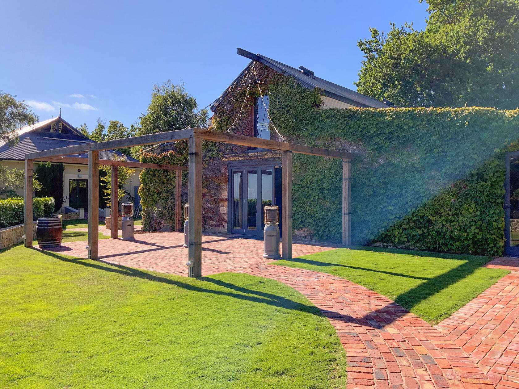 An event space with ivy-covered stone walls, large glass doors, and a brick patio at Mount Lofty House and Estate.