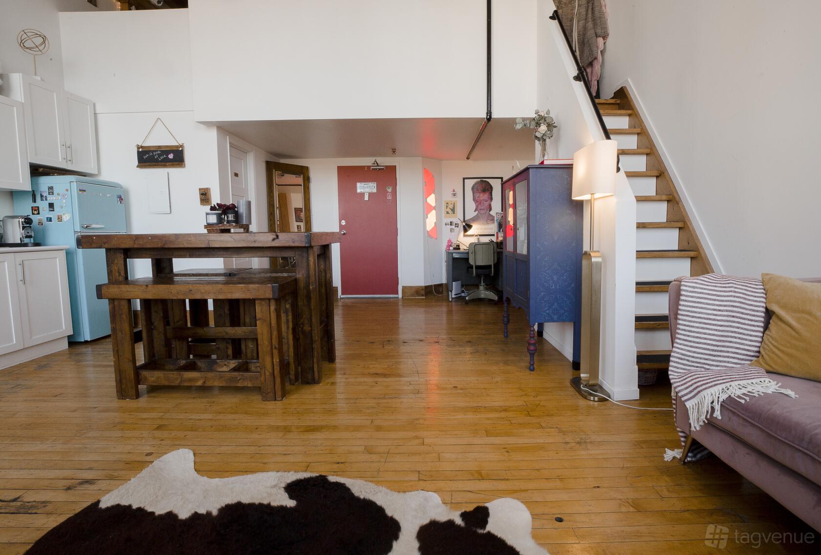 A photo studio with hardwood floors, rustic wooden table, lofted ceiling, and eclectic decor at Brick and Beam Artistic Hard Loft.