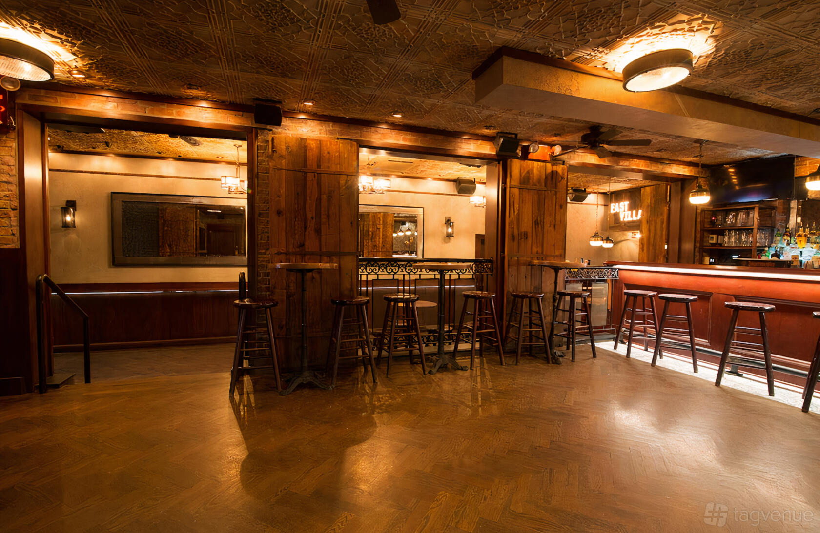 A dining room with wooden bar stools, patterned ceiling tiles, and warm ambient lighting at Downtown Social.