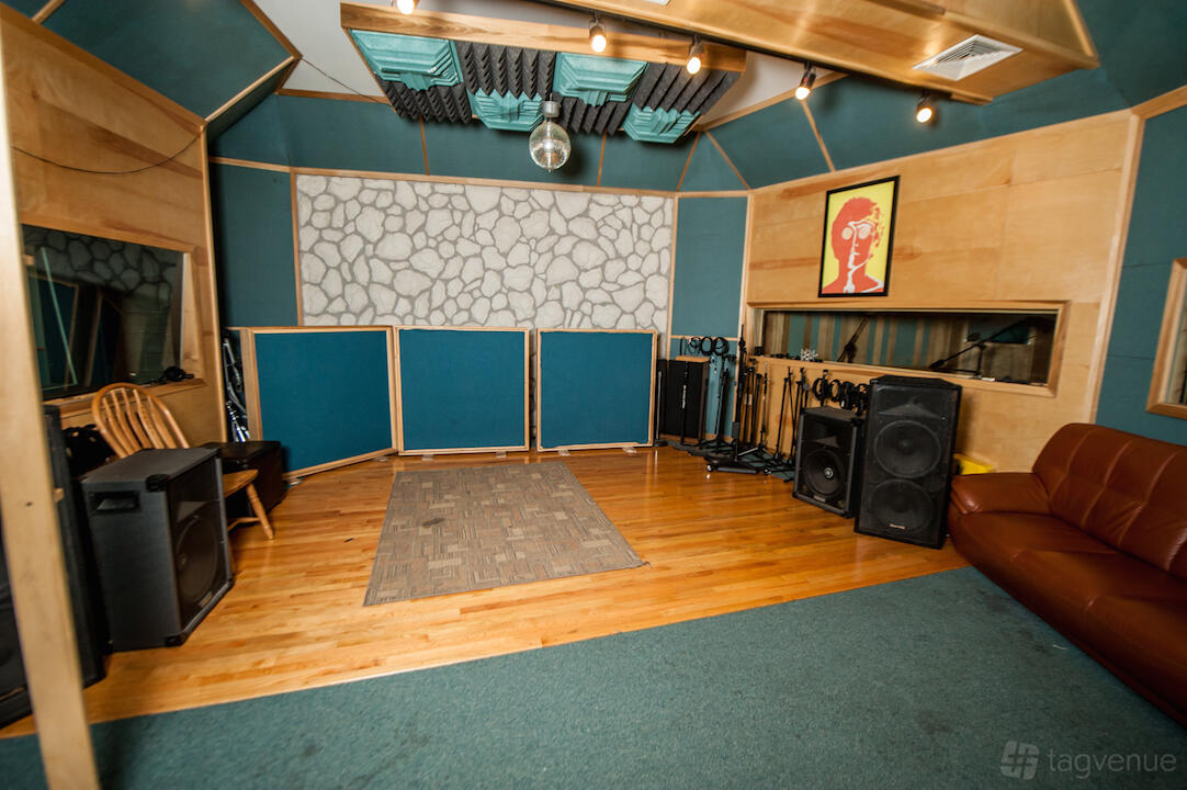 A recording studio with hardwood floors, sound-absorbing panels, and music equipment at Miller Street Studios.