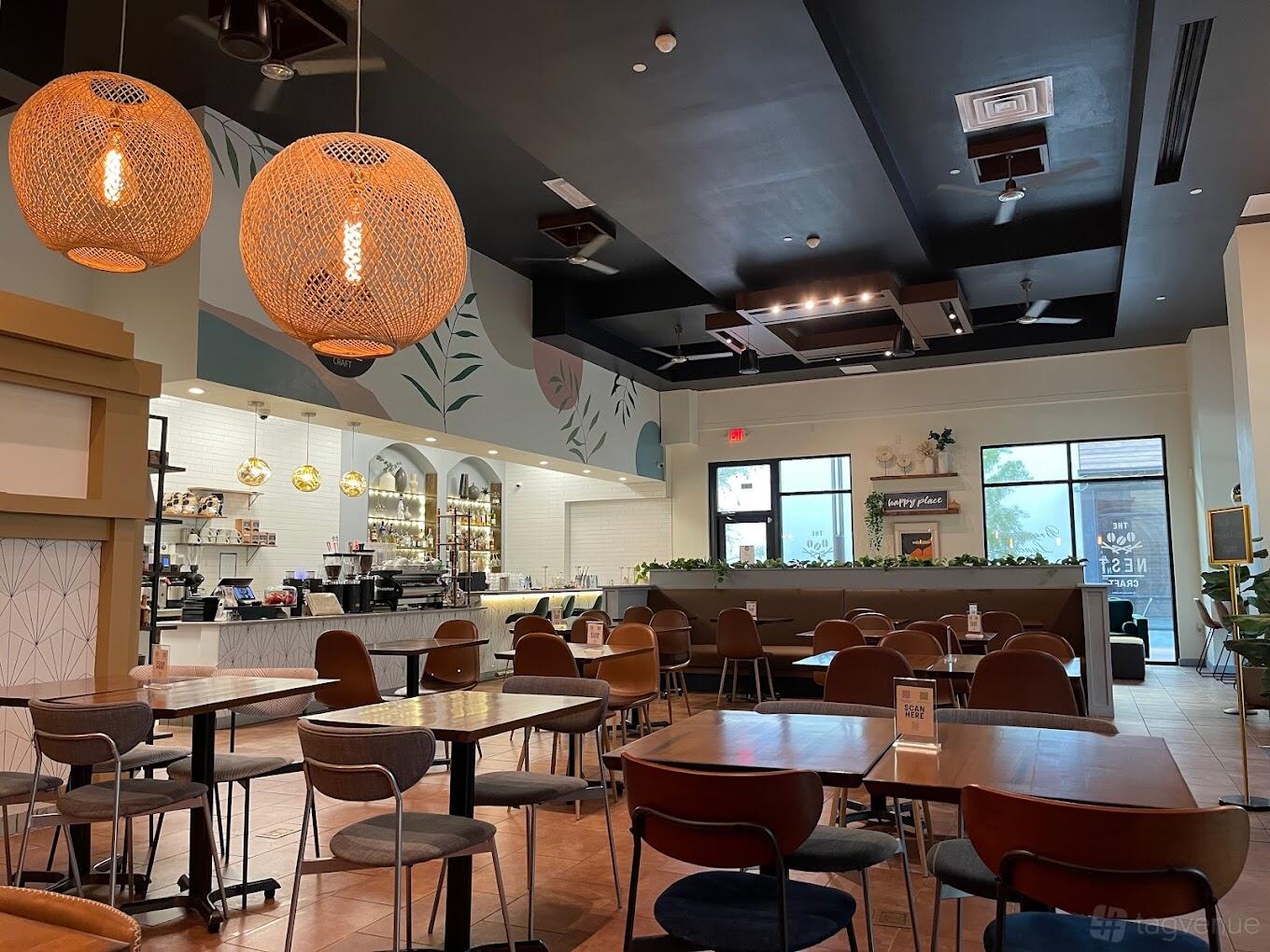 An event space in a restaurant with woven pendant lights, mural ceiling, and open bar at The Nest Craft.