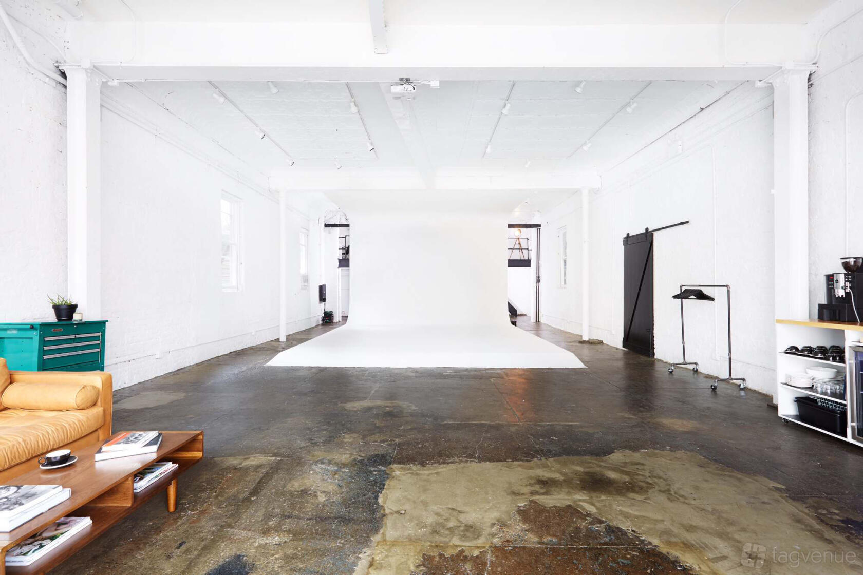A photo and film studio with white cyclorama wall, concrete floors, and lounge seating at Veronica Studio.