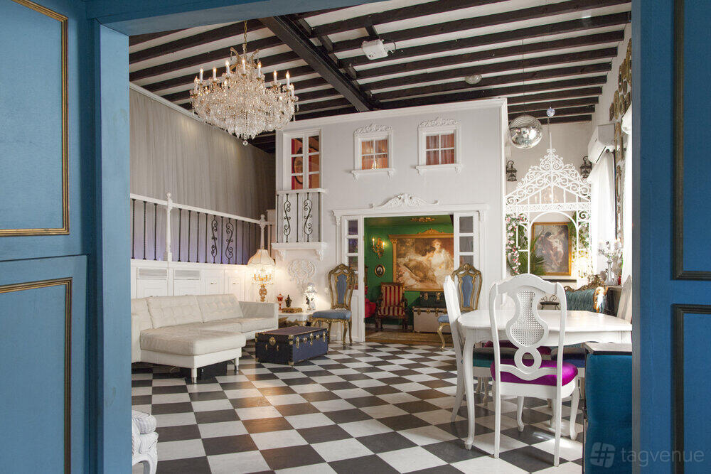 An event venue with checkered floors, vintage chandeliers, eclectic decor, and white seating at The Love Shack.