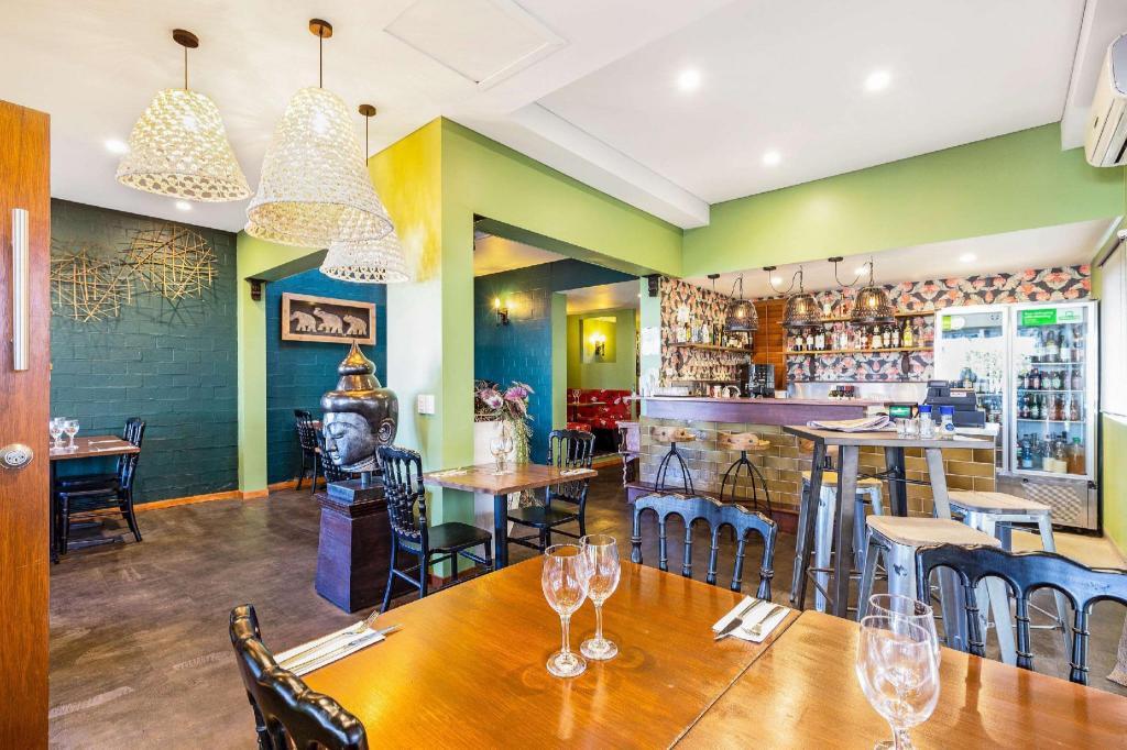 A restaurant in a hotel with wooden tables, black chairs, pendant lights, and a decorative bar at 620 on Brisbane.