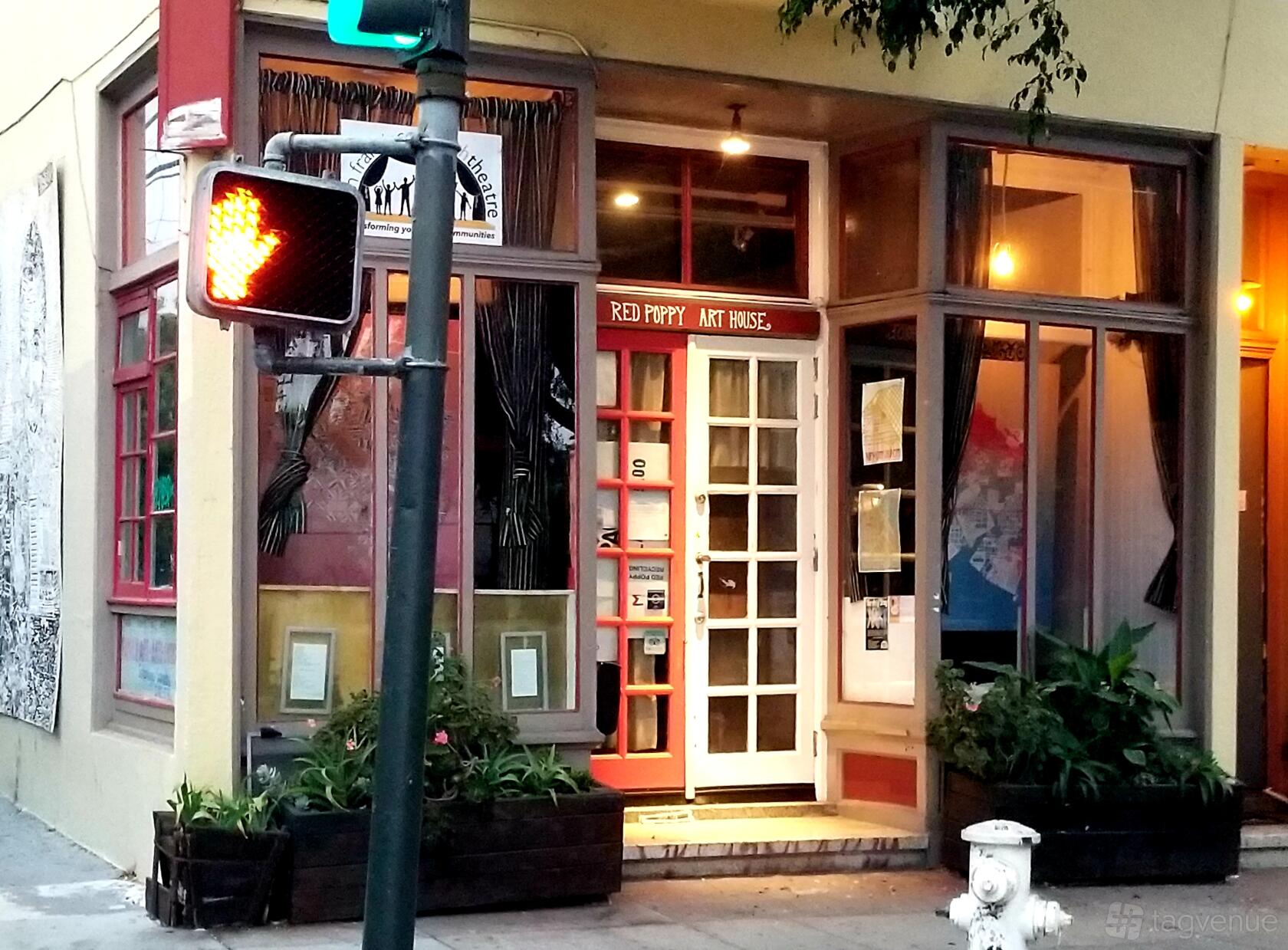 A versatile event space with large front windows, glass-paneled door, and bright signage at Red Poppy Art House.
