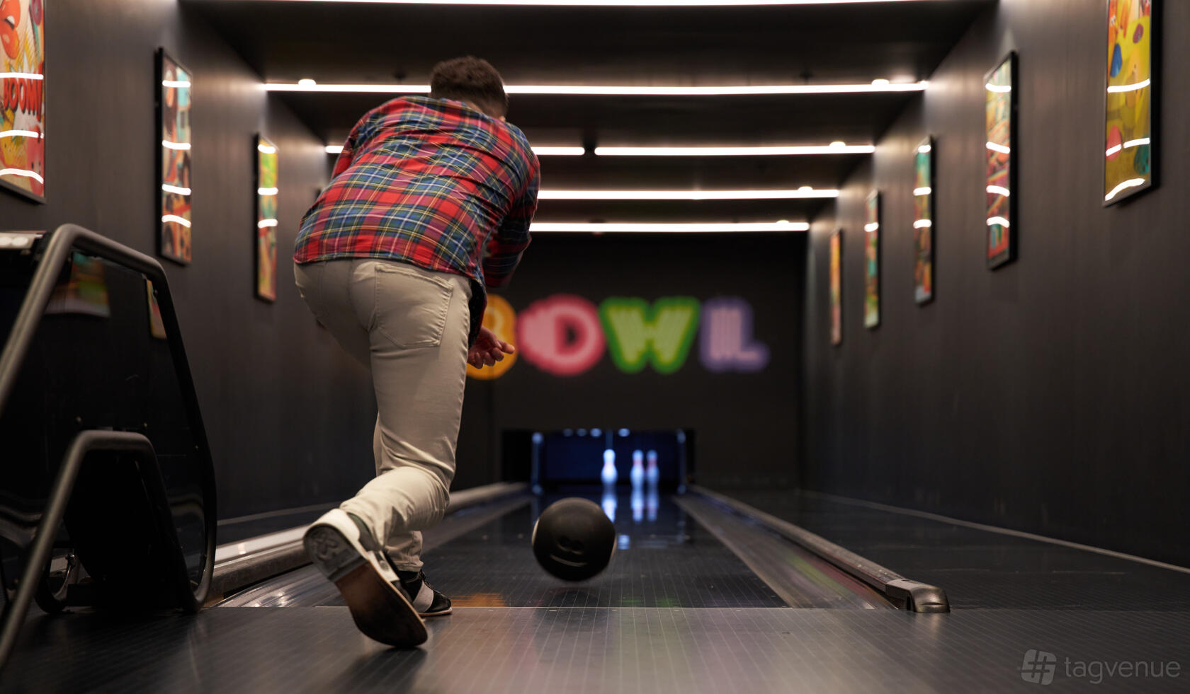 A bowling alley with wooden lanes, colorful signage, and overhead lighting at The Westminster Bar & Grill.