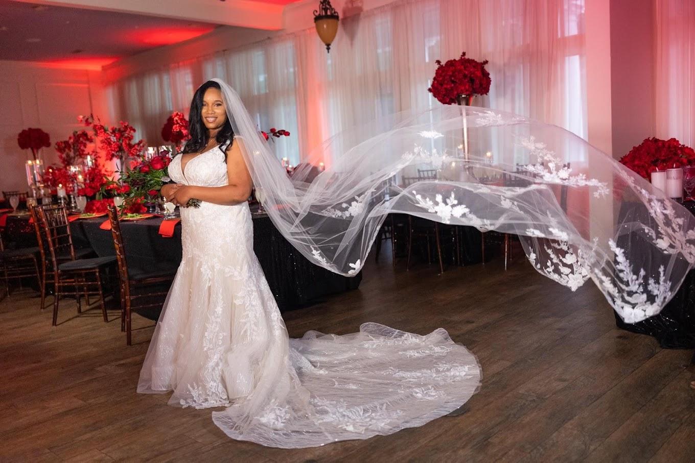 An event venue with wood flooring, red floral centerpieces, and candlelit tables at Orleangham Event Facility.