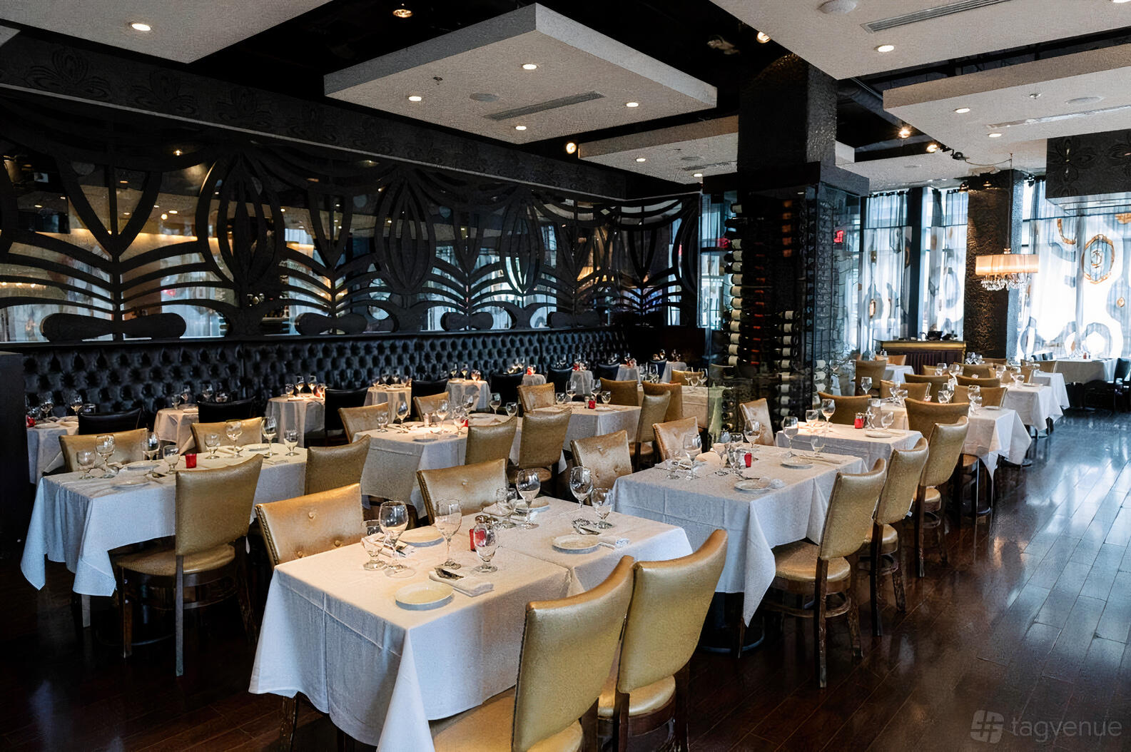 A restaurant dining area with white tablecloths, leather chairs, and a glass wine rack at Station 4.